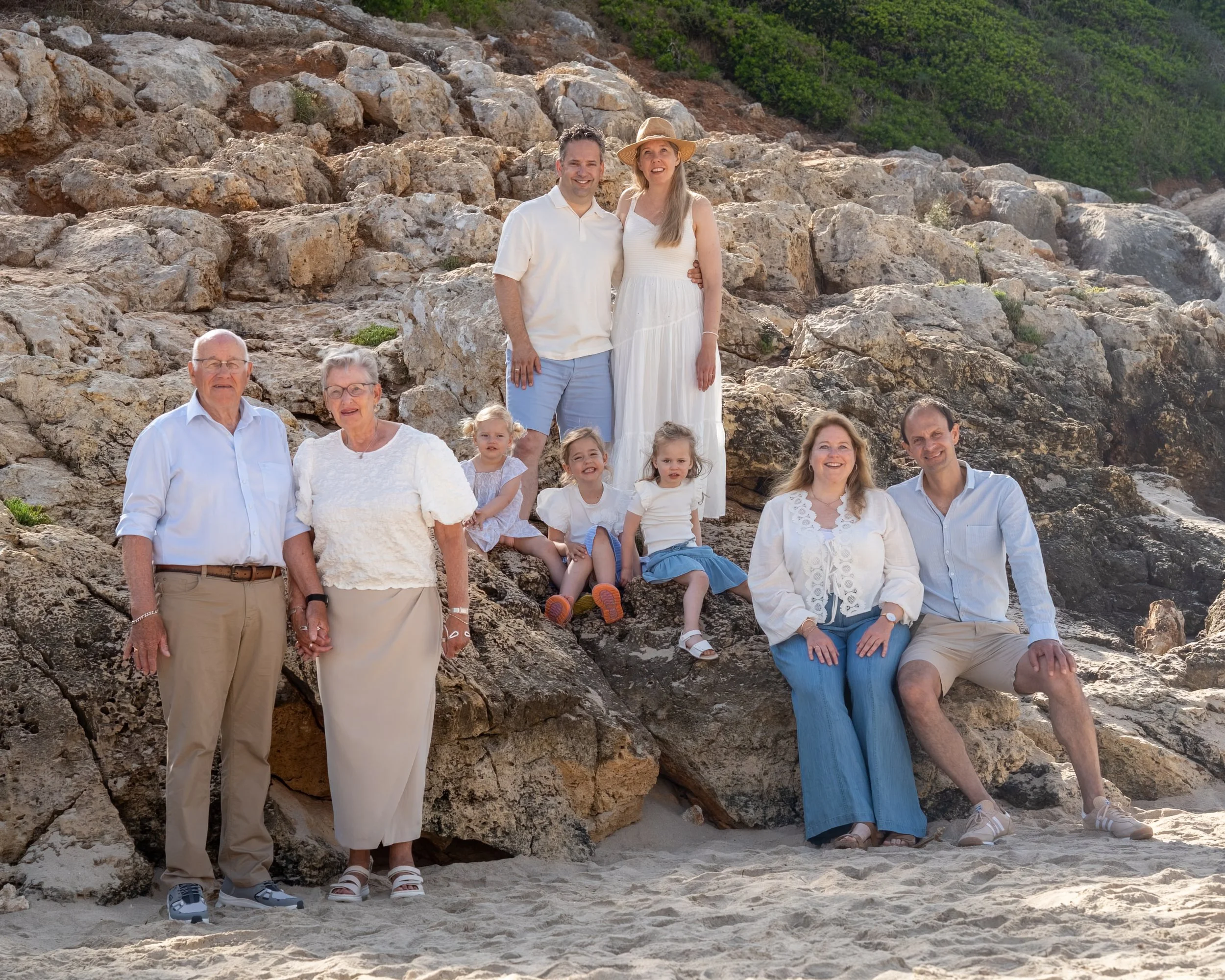 Familie fotoshoot met opa, oma en twee gezinnen zittend op rotsen op Mallorca
