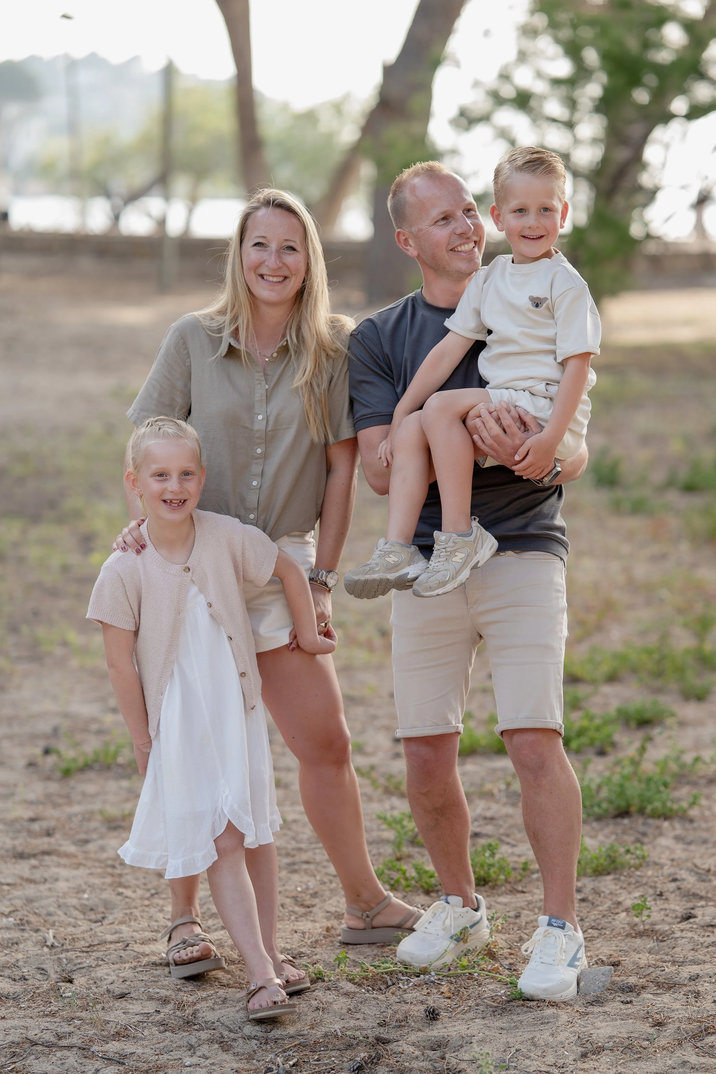 Gezinsportret tijdens een familiefotoshoot op Mallorca, met lachende ouders en hun zoon en dochter tijdens een ontspannen en natuurlijke fotosessie.
