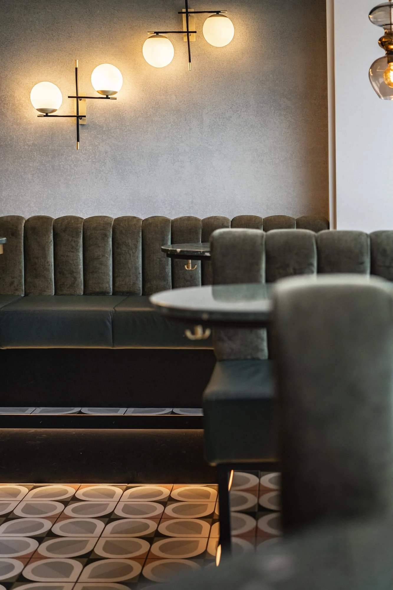Stilvoller Bar- und Lounge-Bereich im Rio Café & Cocktailbar in Dornbirn mit dunklen Samt-Sofas, runden Tischen und warmen Wandlampen.