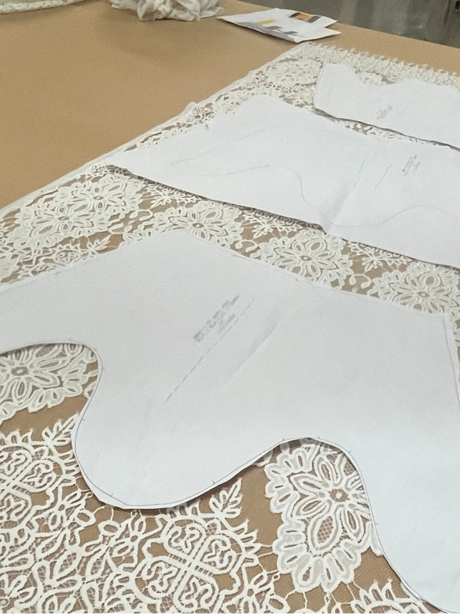 Patterned lace tablecloth with large paper pattern pieces for sewing, including a pants leg.