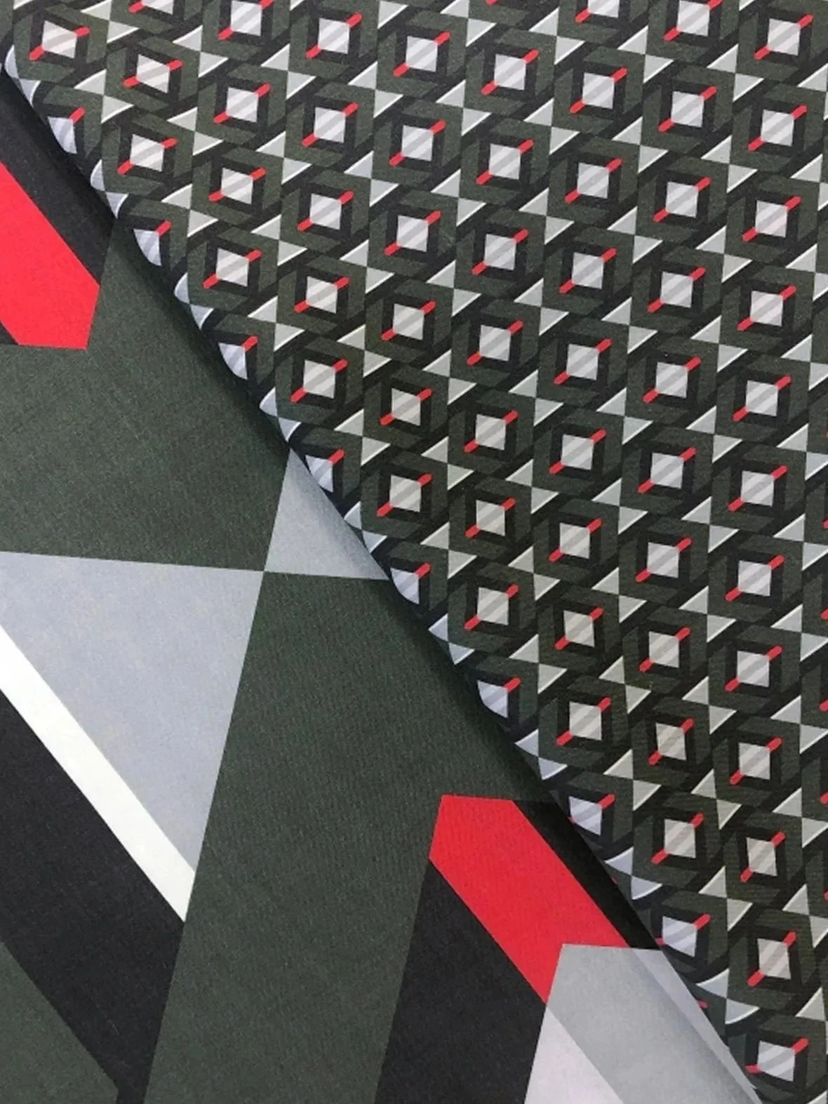 Close-up of a table with a black, white, red, and gray geometric patterned cloth, and a floor with similar geometric tile patterns in black and gray.