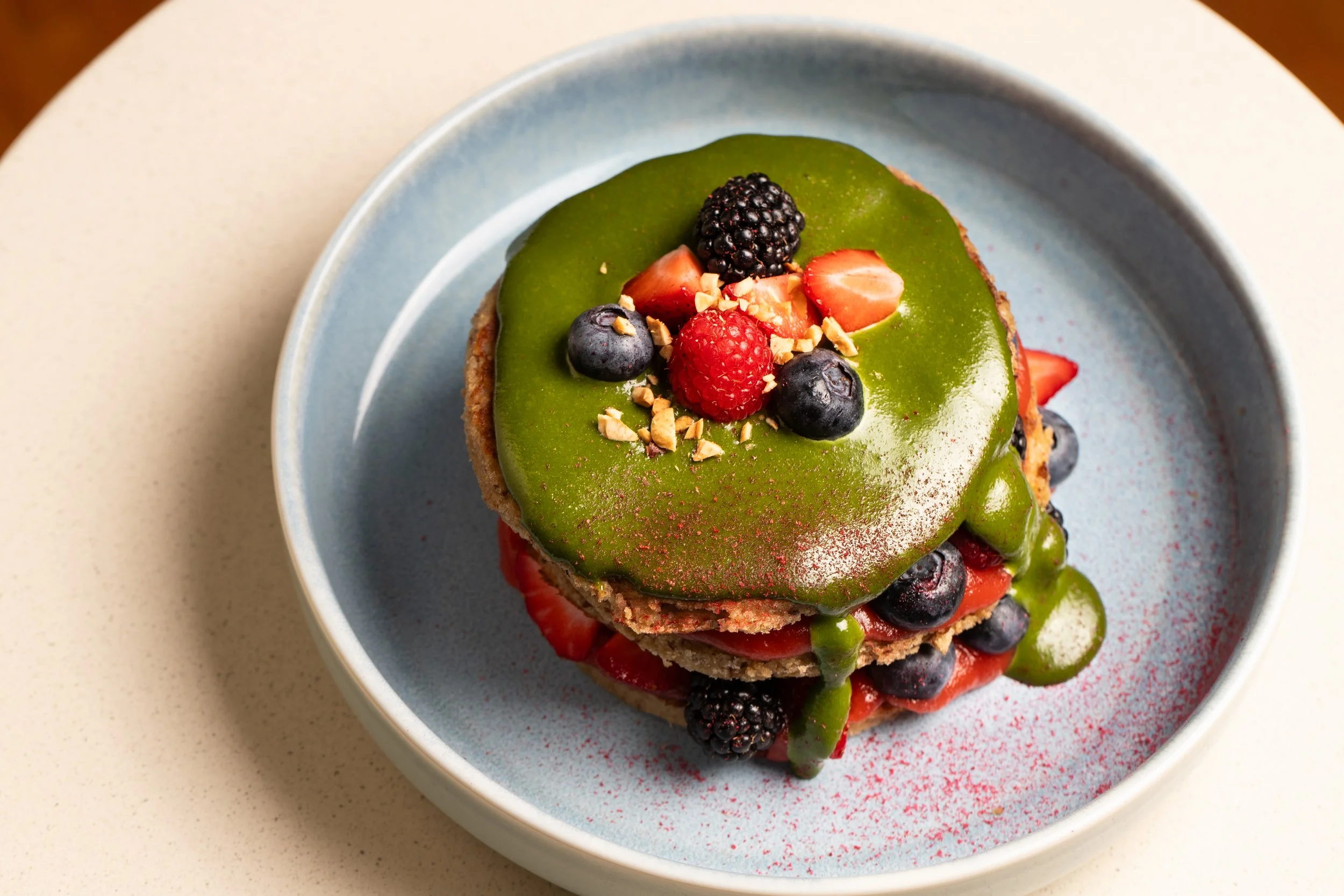 Vegan matcha pancakes, gluten free, topped with various berries and chopped nuts.