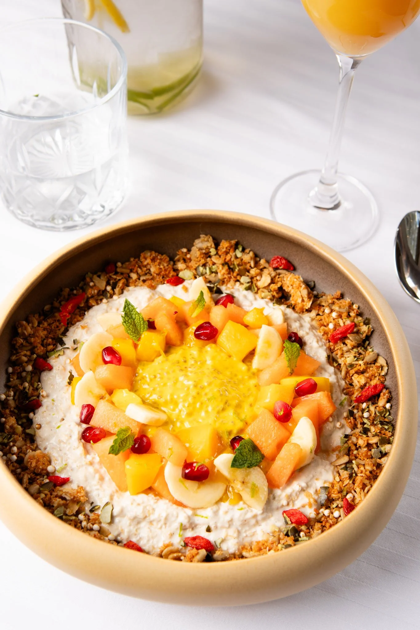 Chia pudding breakfast with chopped melon, bananas, and pomegranate seeds garnished with mint leaves in a large bowl.