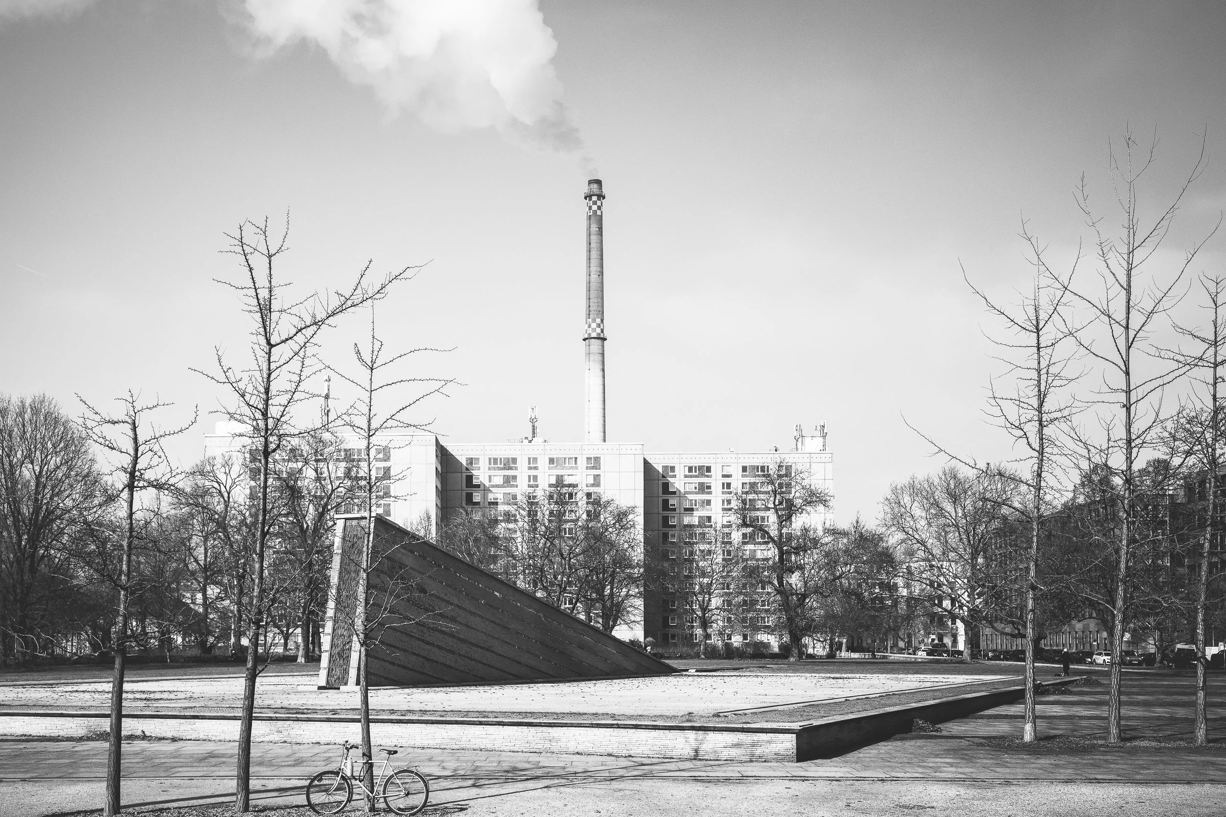 Park i komin przemysłowy w Berlinie - czarno-biała fotografia miasta pomiędzy zielenią, przemysłem i ciszą.