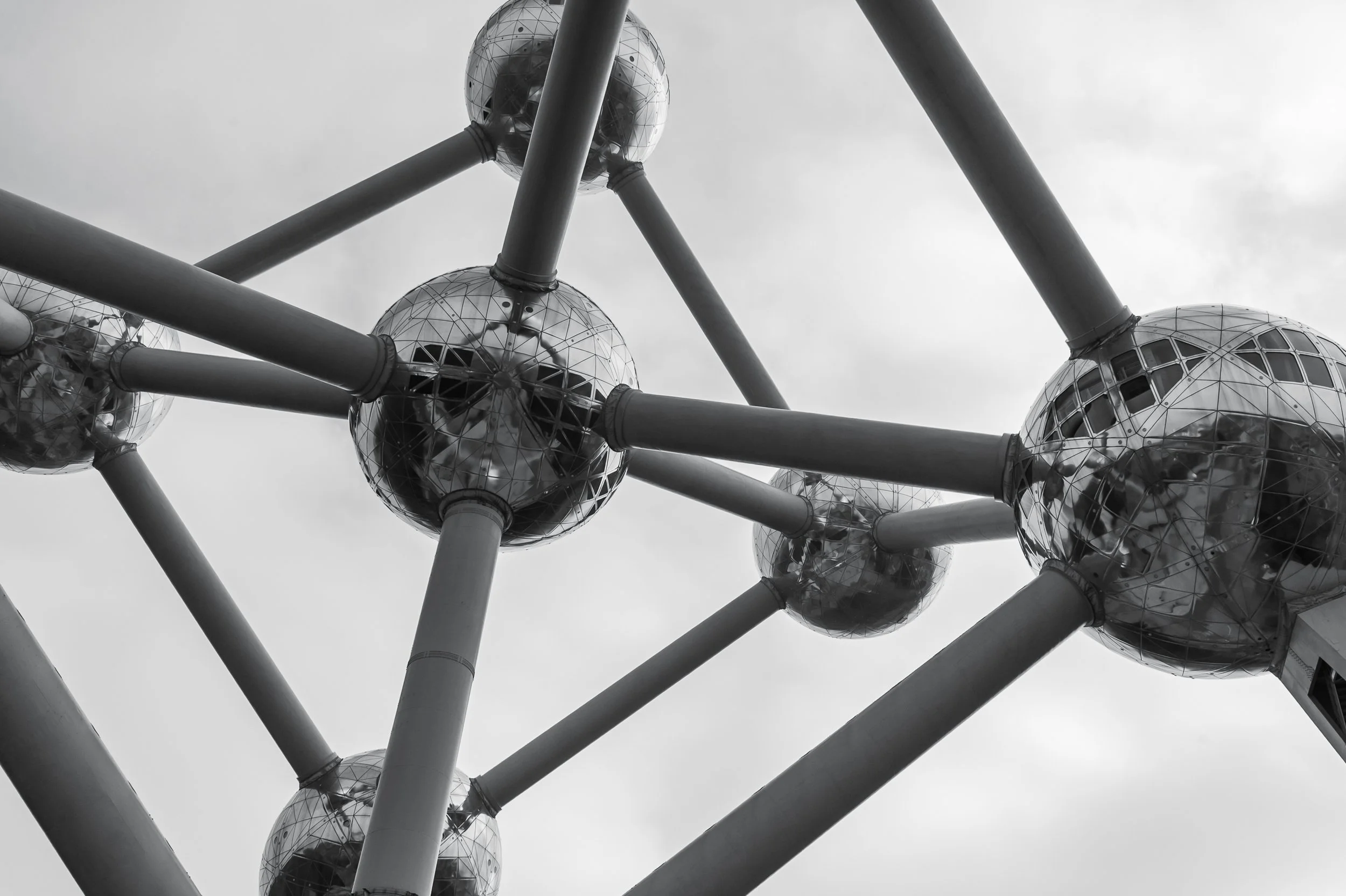 Centralna kula Atomium w pionowym kadrze - czarno-biała fotografia architektury futurystycznej i miejskiego światła.