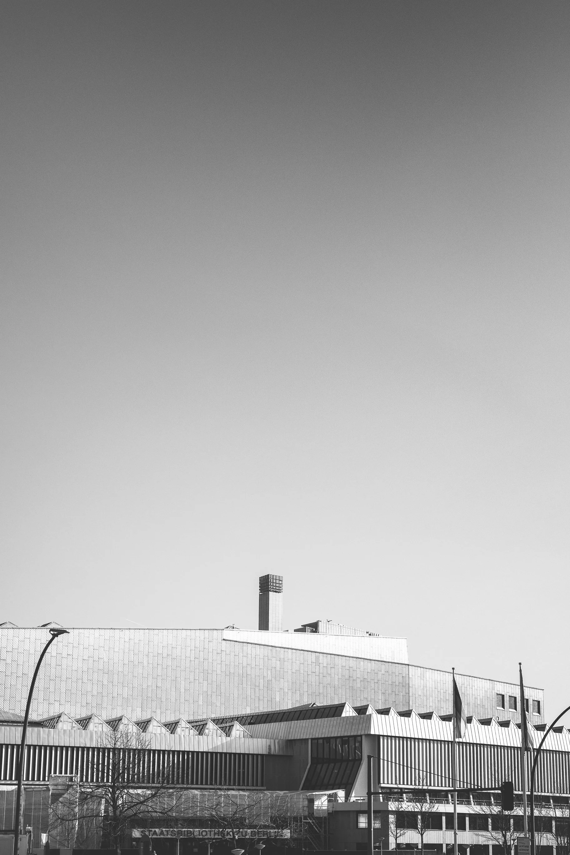 Minimalistyczny kadr nieba i niskiej zabudowy Berlina - czarno-biała fotografia miasta z dużą przestrzenią oddechu.