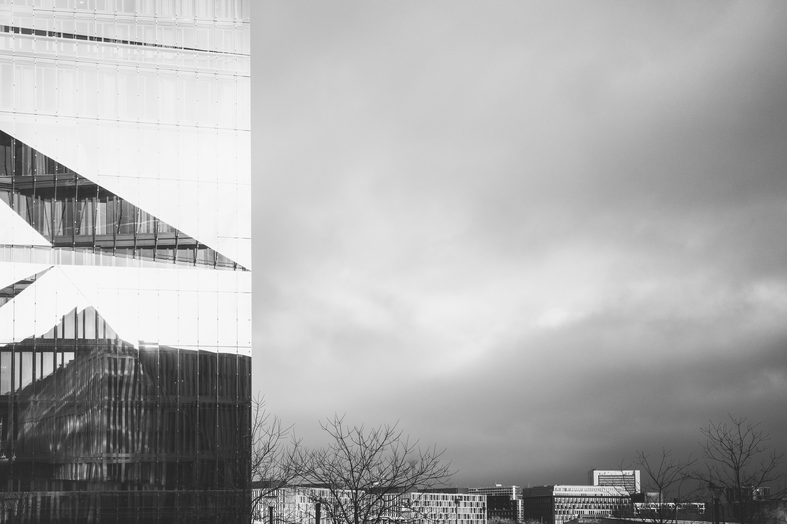 Fragment nowoczesnej architektury Berlina pod pochmurnym niebem - czarno-biała kompozycja formy, światła i miasta.