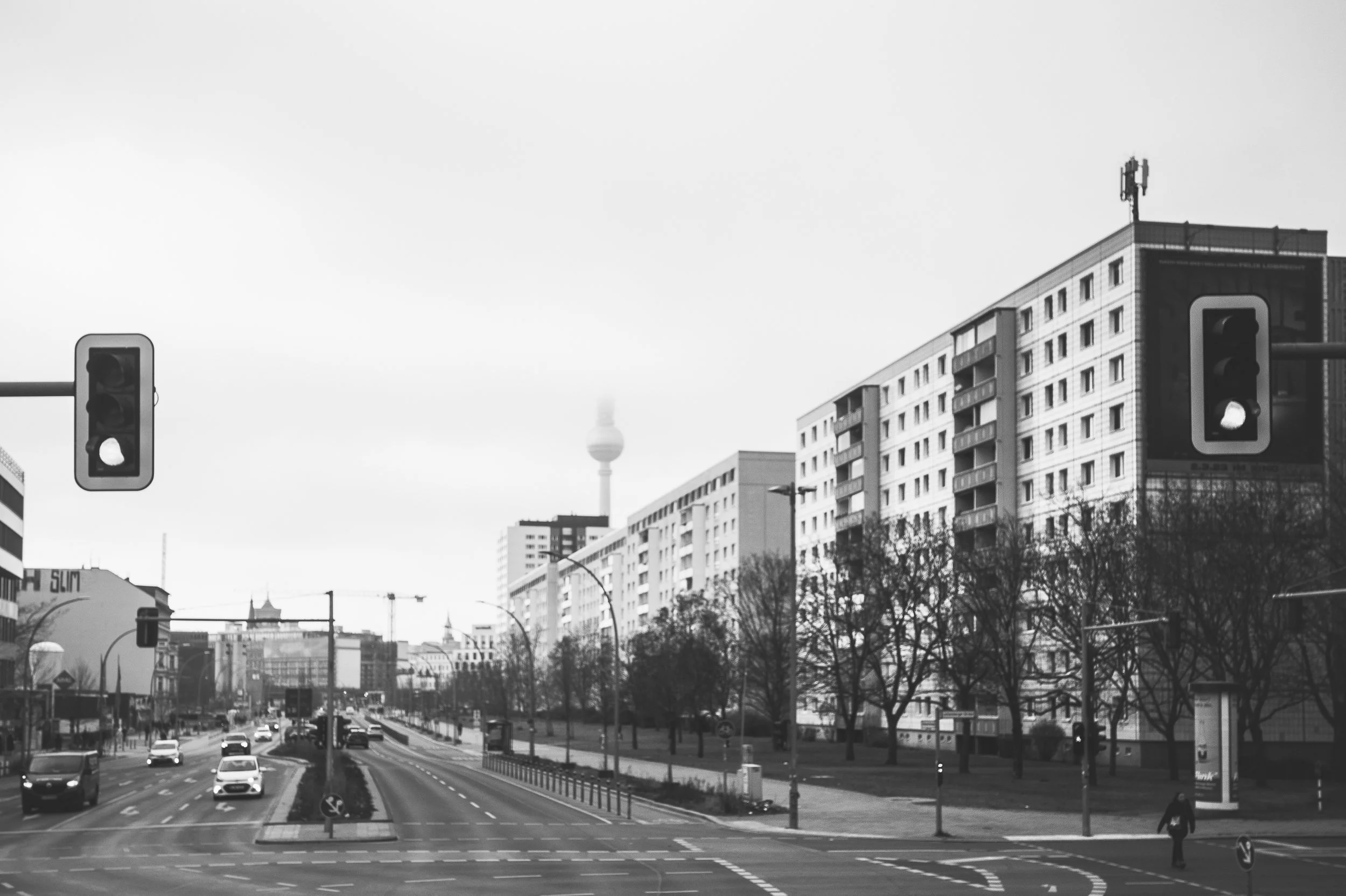 Berlińska arteria z wieżą telewizyjną w oddali - czarno-biała fotografia ulicy, ruchu i miejskiej osi.