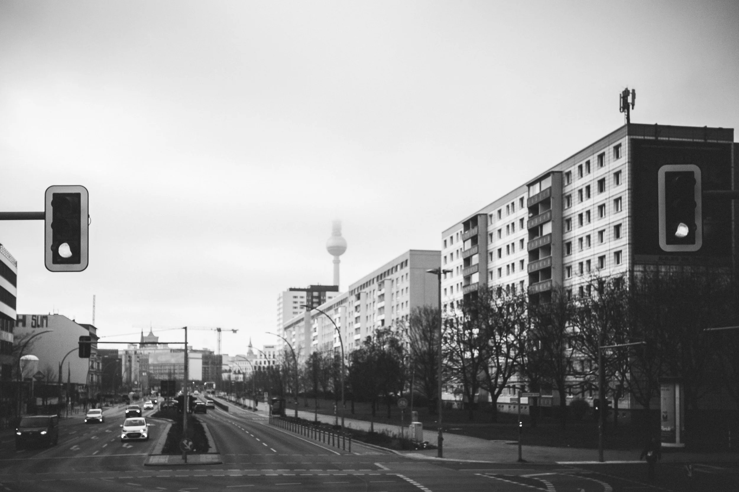 Berlińska ulica z wieżą telewizyjną w tle - czarno-biała fotografia miasta, ruchu i architektury codzienności.