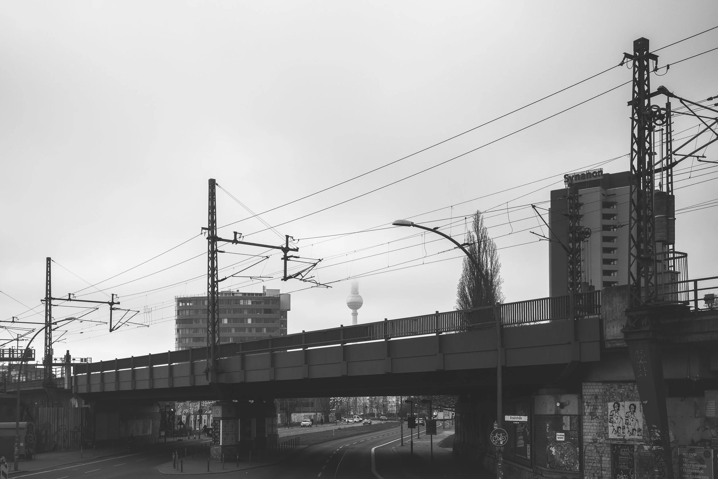 Most kolejowy i linie trakcyjne w Berlinie - czarno-biała fotografia infrastruktury miejskiej, torów i surowego nieba.