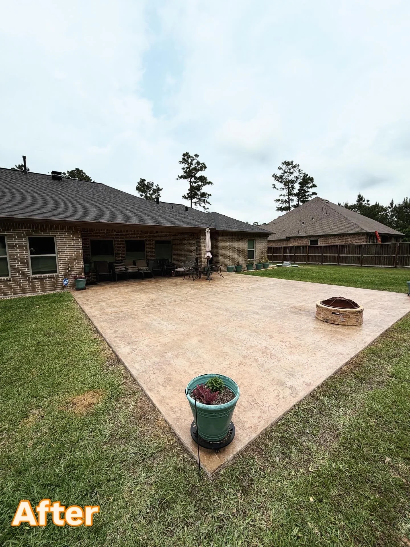 Backyard with a newly finished concrete patio, outdoor furniture, potted plants, and a fire pit