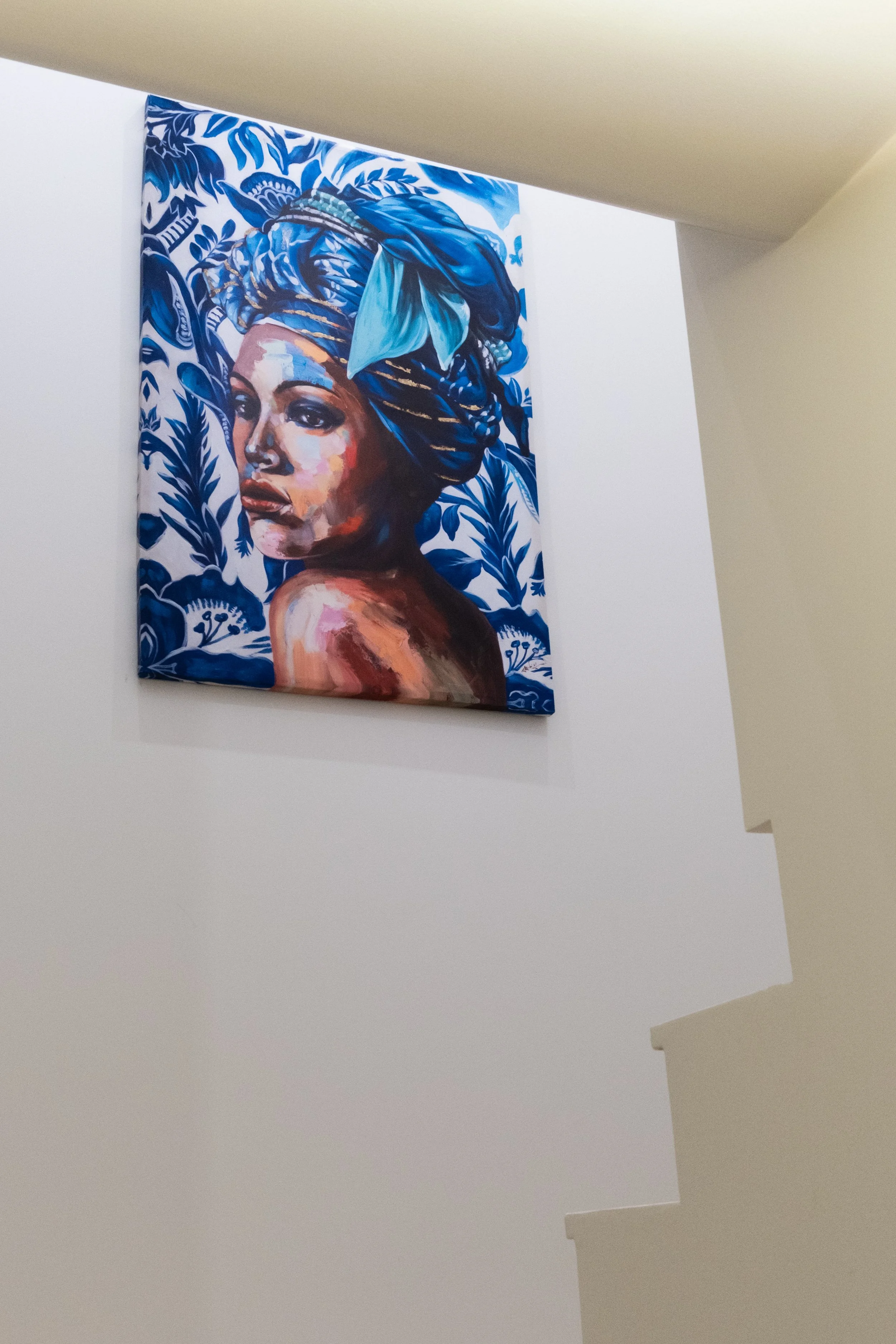 Quadro de pintura de uma mulher com turbante azul, com fundo de folhas azuis e detalhes florais.
