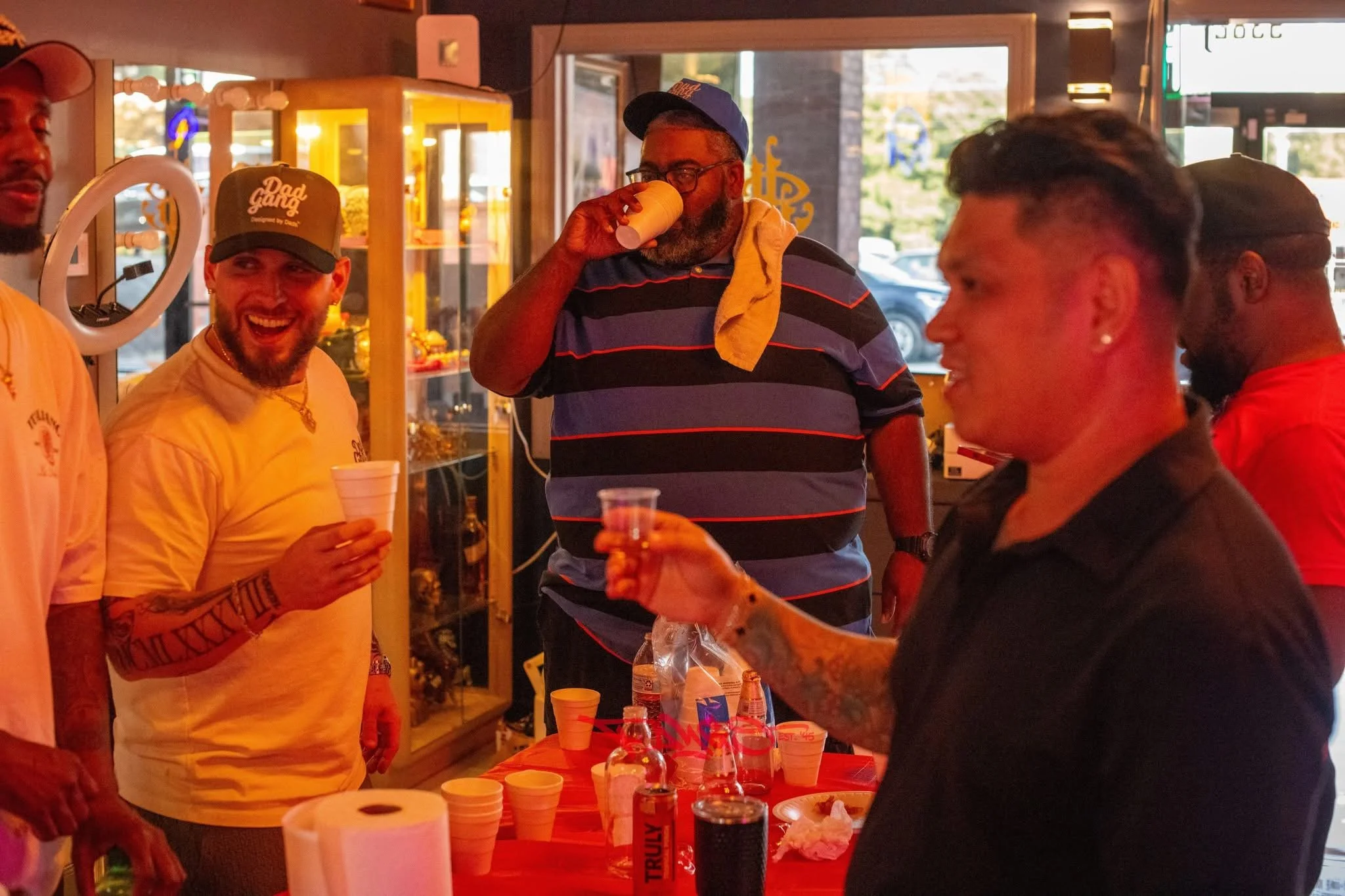 Group of people socializing inside a bar, with drinks in hand and smiling.