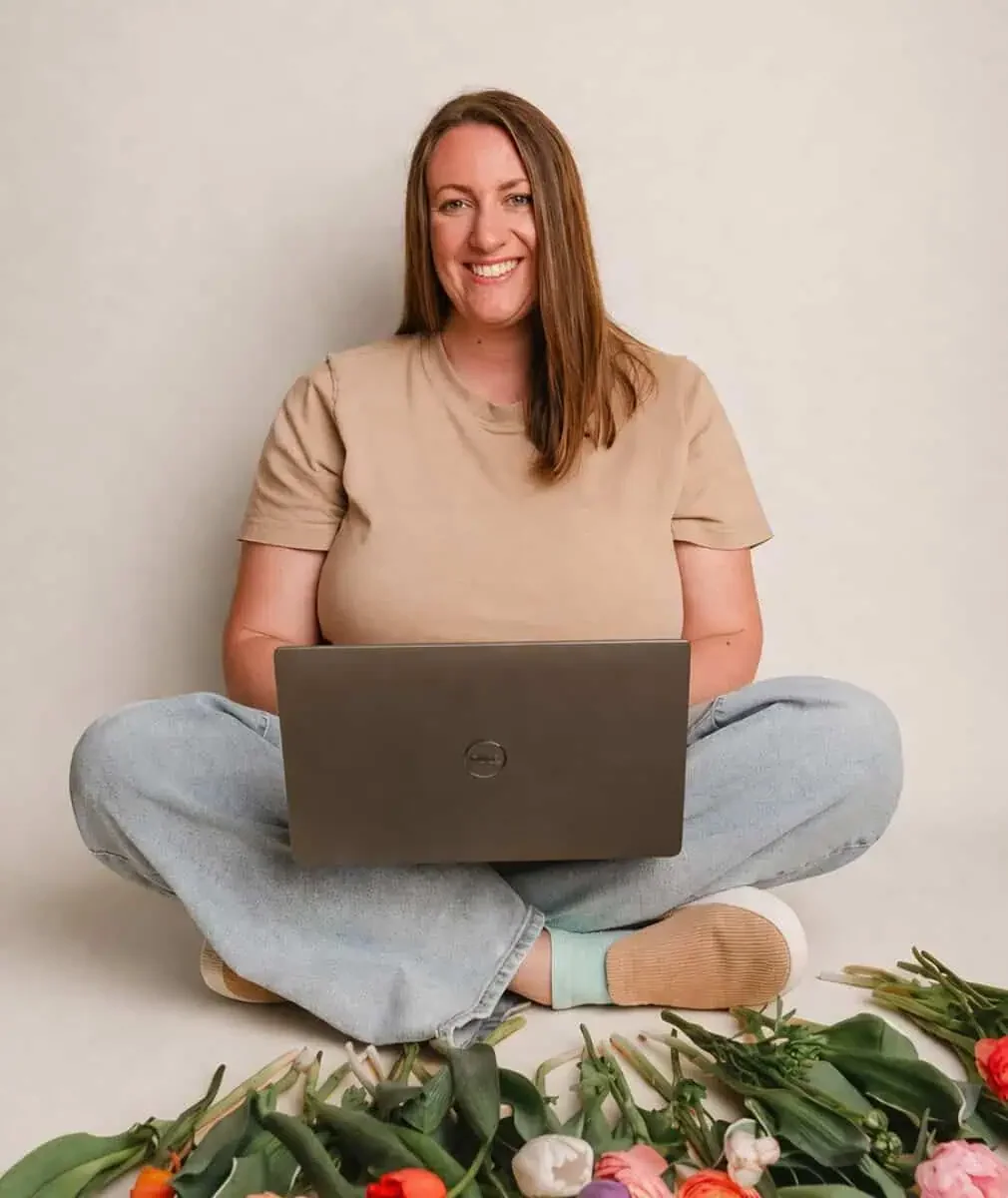 julie kelmens sitting with laptop and flowers laid out infront of her