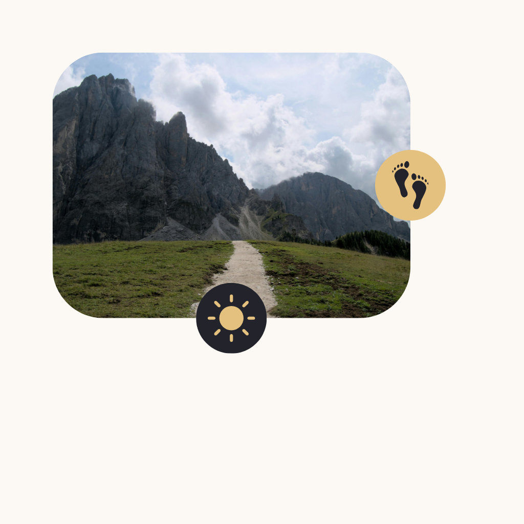 Mountain trail leading towards rocky mountains under a partly cloudy sky.