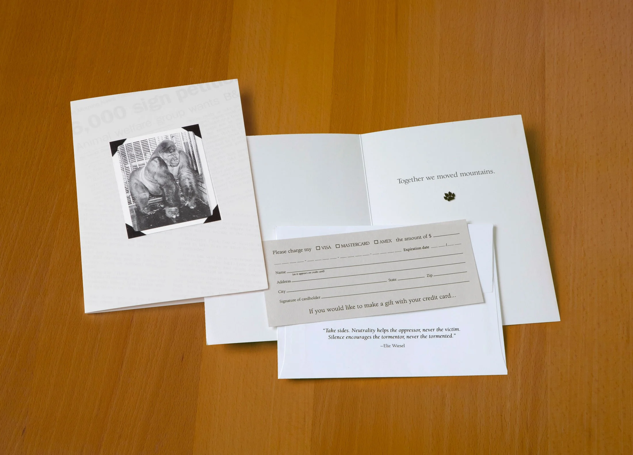 A pamphlet with a picture of a gorilla, a card for charging a credit card, and a note with the message "Together we moved mountains" on a wooden surface.