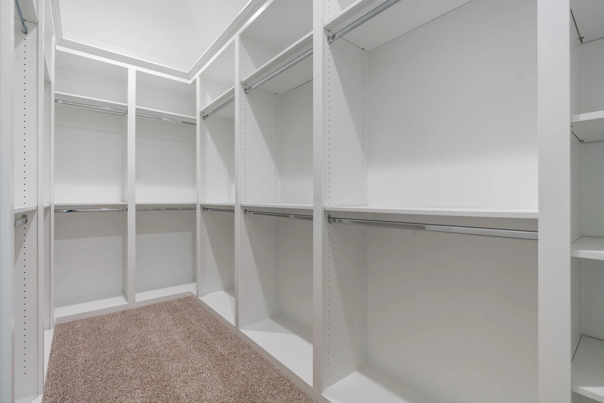 Empty white walk-in closet with shelving and hanging rods