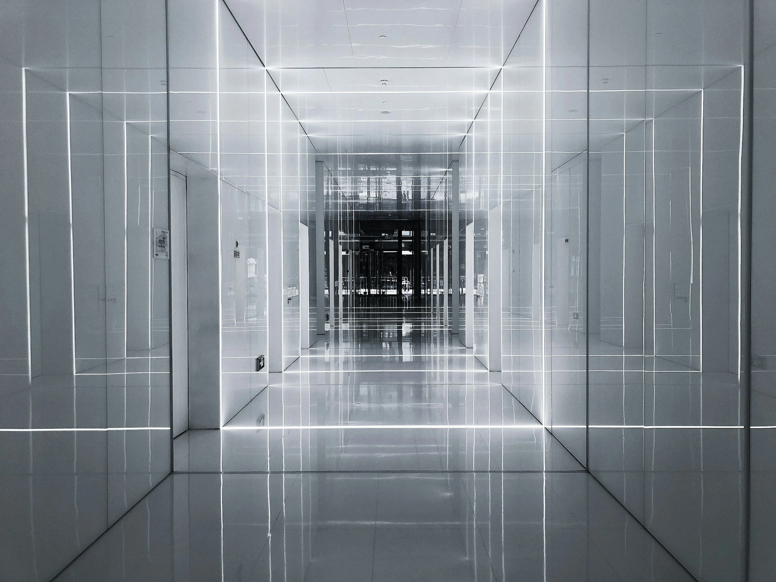 A modern, sleek hallway with reflective surfaces and illuminated white lines creating a geometric pattern.