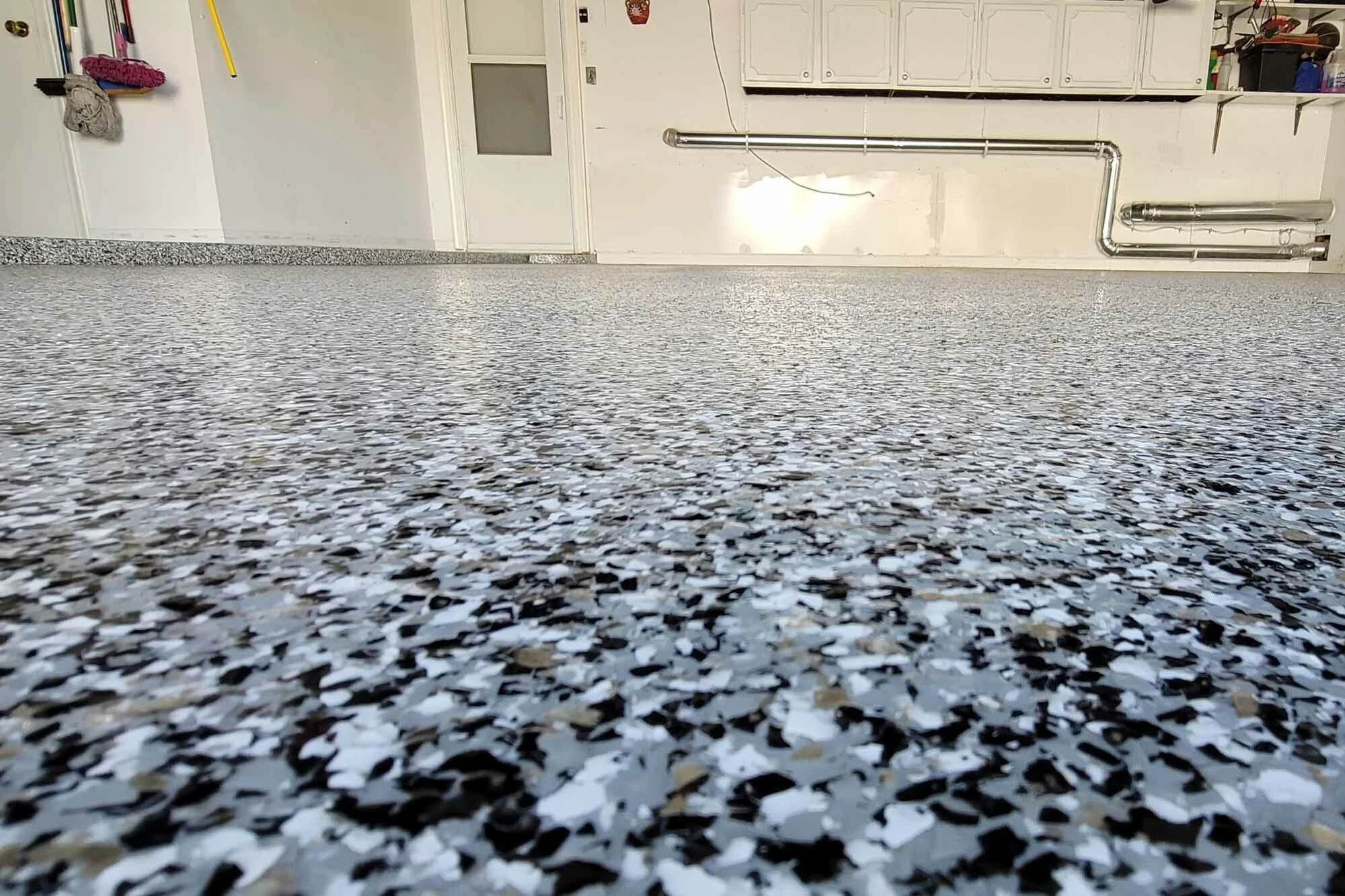 Close-up of a terrazzo floor with small, irregularly shaped chips in black, white, beige, and gray colors.