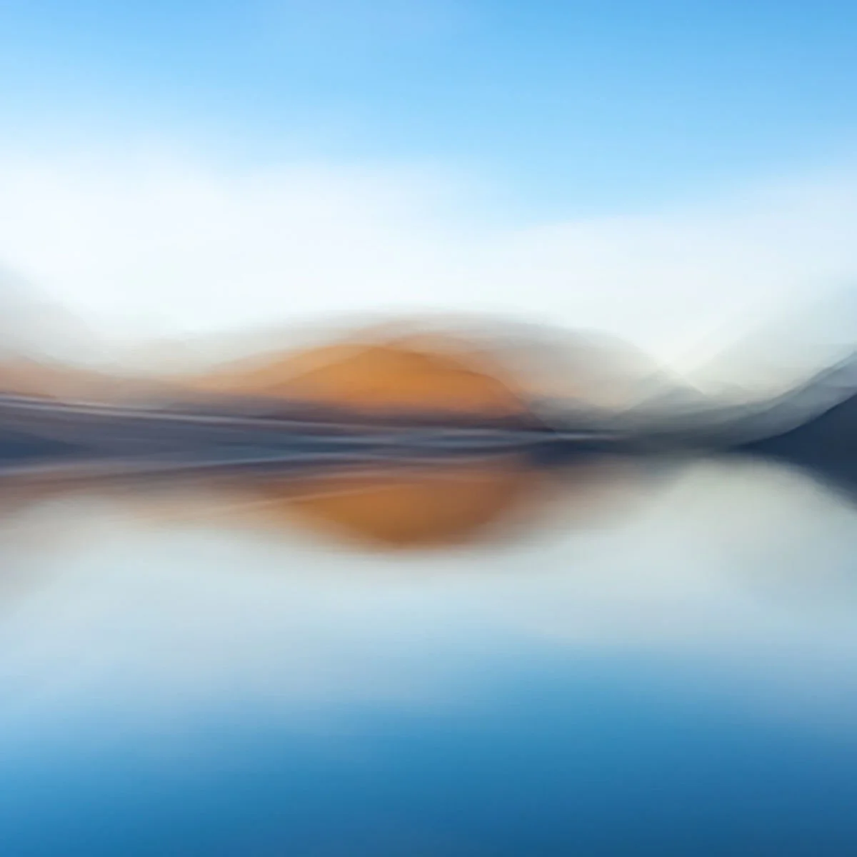 Intentional camera movement ICM image greated to give impressions of a landscape of mountains, water, and sky with hints of orange and blue.