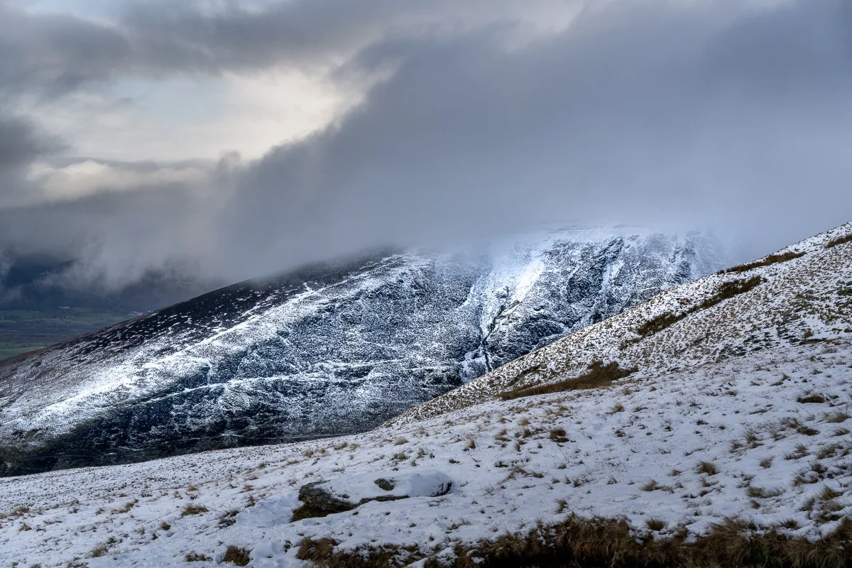 Snow-covered mountain landscape with cloudy sky overhead.