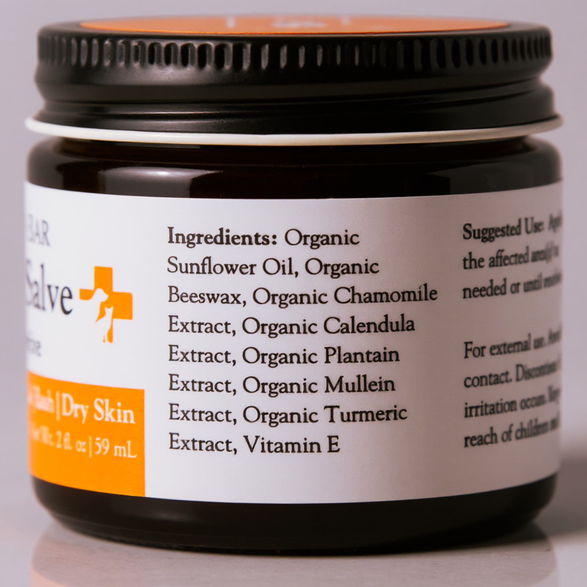Close-up of a brown bottle with a white label, showing ingredients such as organic sunflower oil, organic beeswax, organic chamomile extract, and organic calendula extract.