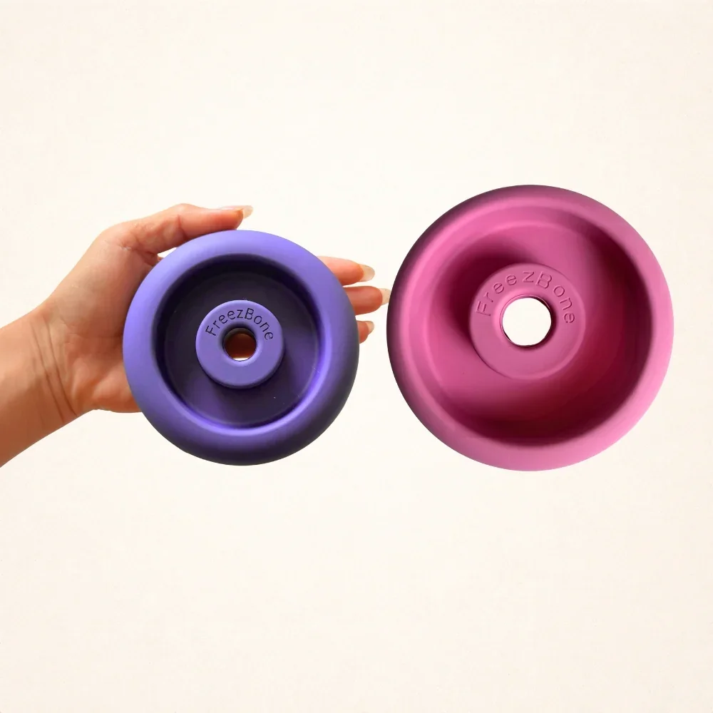 Two foam rollers labeled 'FreezBone', one purple and one pink, held against a plain white background, with the purple roller held by a person's hand.