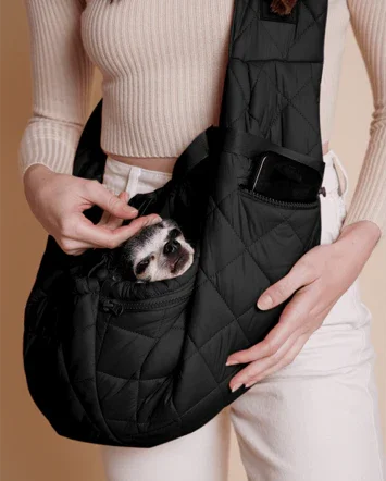 Minimal black pet sling bag styled for urban travel with dog inside