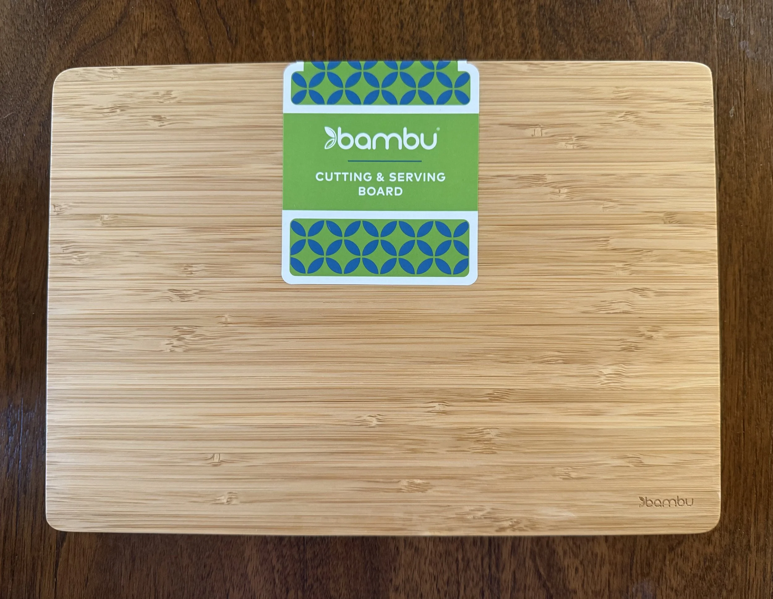 Bambu cutting and serving board made of bamboo, placed on a wooden surface.