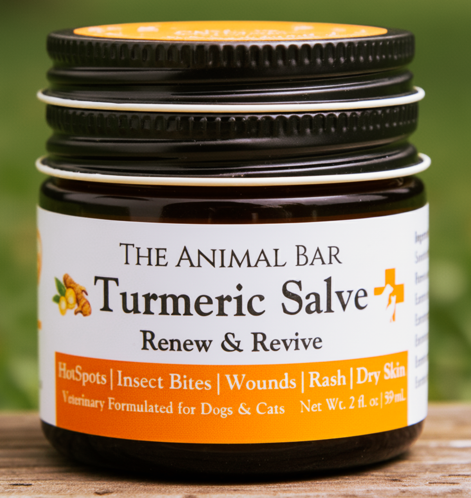 Close-up of a bottle labeled 'The Animal Bar' with a focus on the section reading 'Turmeric Salve' and listing benefits such as hot spots, insect bites, wounds, rash, and dry skin. The bottle is placed on a wooden surface with a green blurred background.