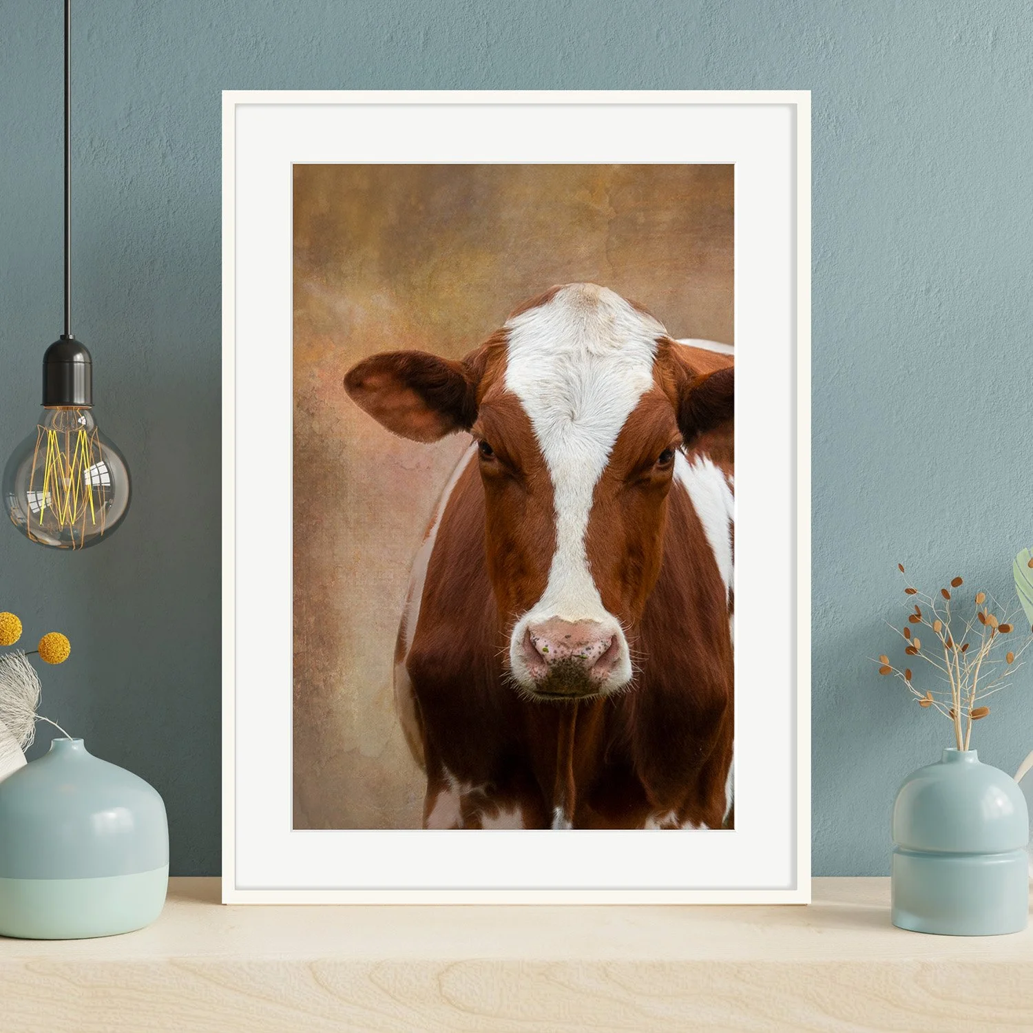 Framed portrait of brown and  white cow in a room