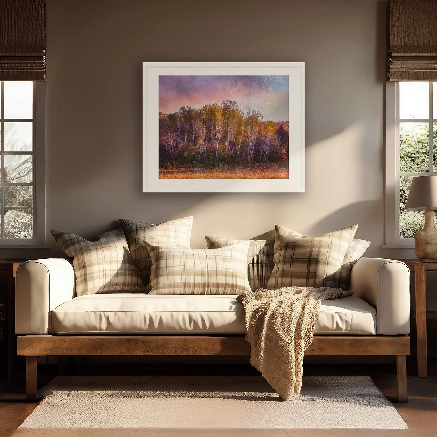 And So It Goes by Laura Berman, a framed limited edition fine art print of fall birches, above a cream sofa in a sunlit living room.