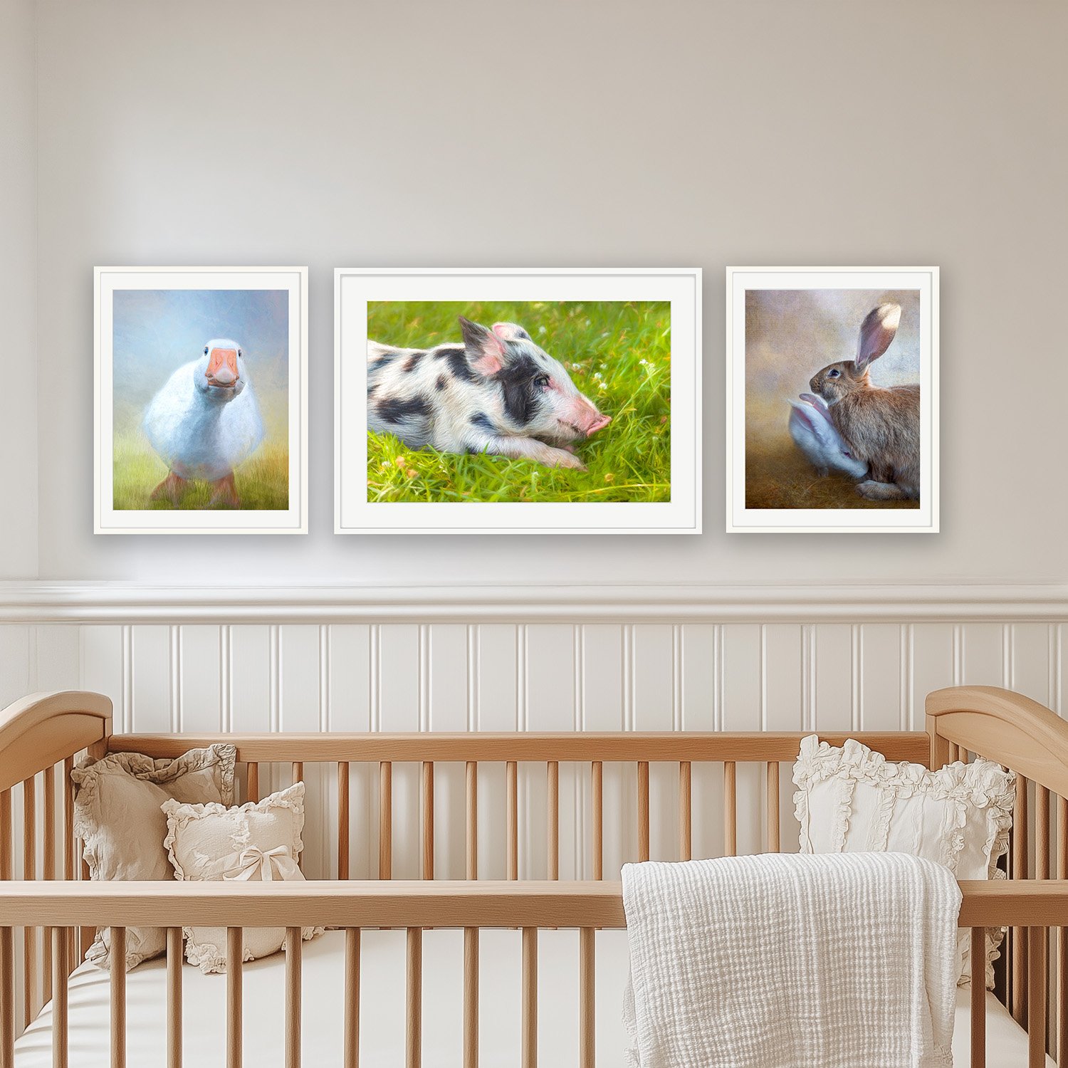 Three painterly fine art prints by Laura Berman, framed above a crib in a soft neutral nursery: "Loosey Goosey", "We Laughed in the Sun and Kissed the Lovely Grass", and "Support System".