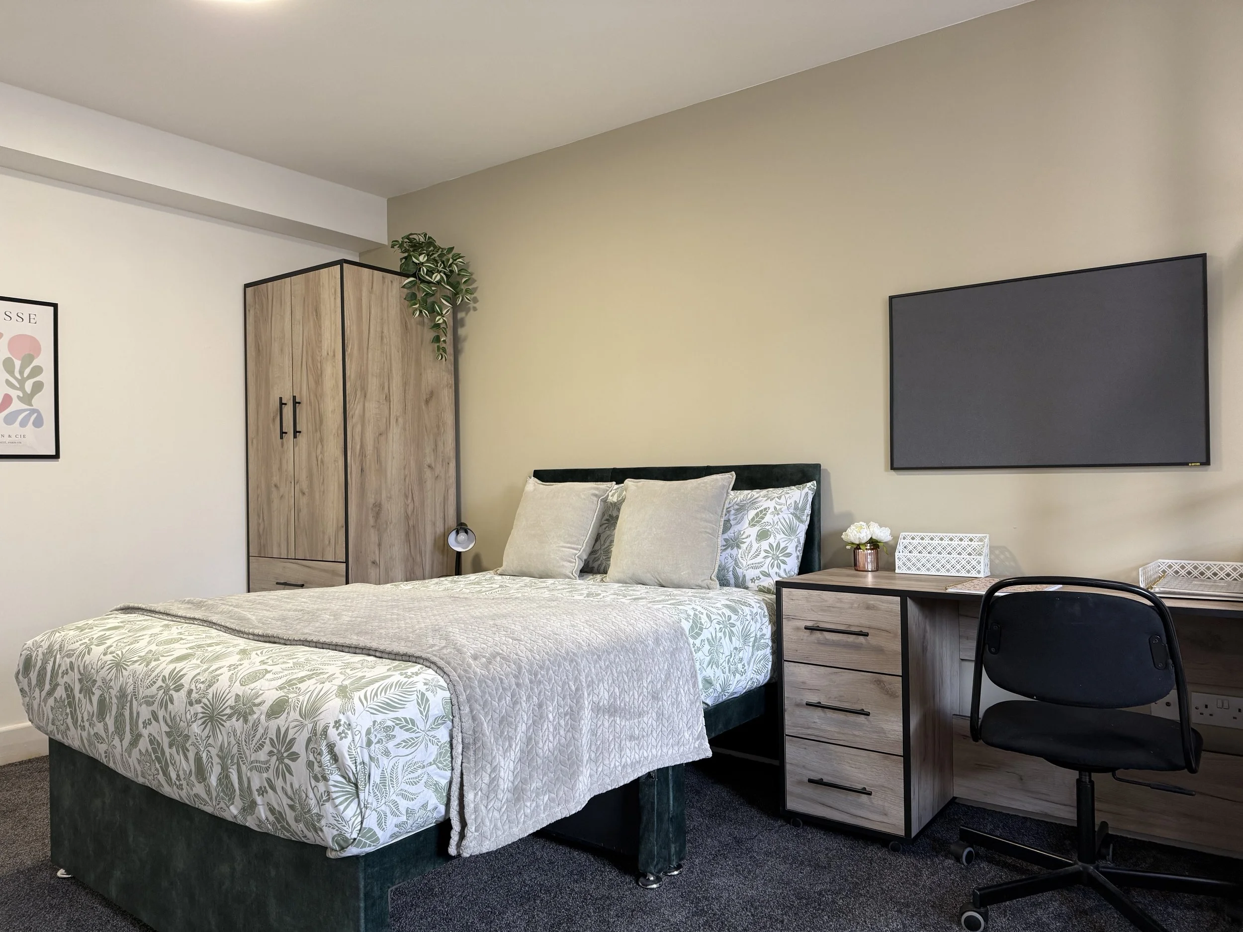 Modern bedroom with a bed, wardrobe, wall-mounted TV, and a desk with a chair.