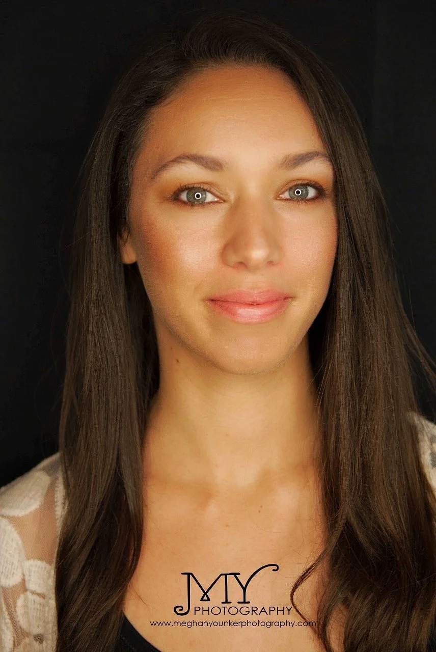 A woman with long brown hair and gray eyes, wearing a black top and a cream-colored lace cardigan, smiling softly against a black background. The photo is a professional portrait with a logo at the bottom that says "MY Photography" and a website link.