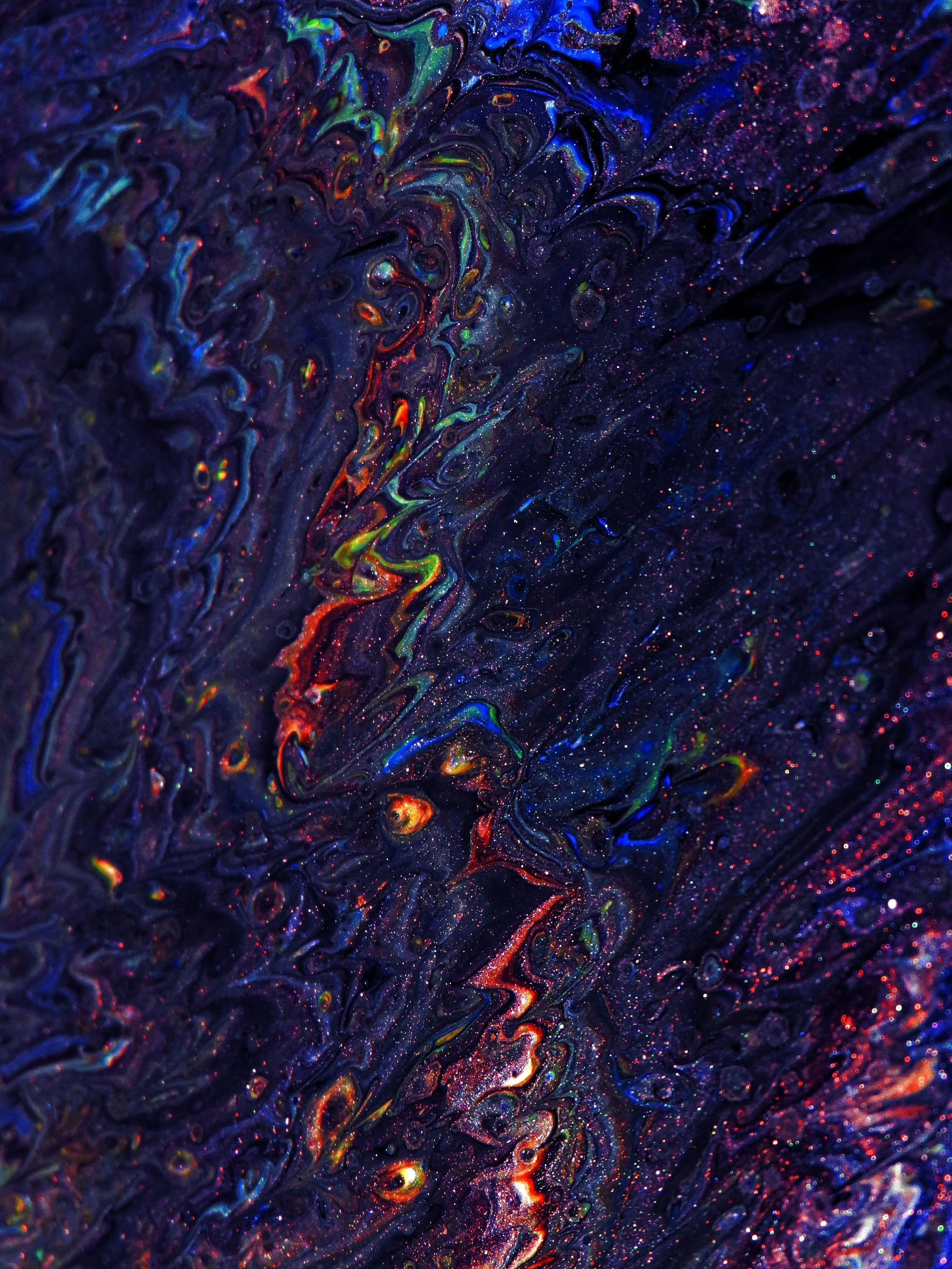 Abstract artwork with dark blue background and swirling, iridescent colors including red, green, yellow, and orange, resembling a cosmic or galaxy scene.