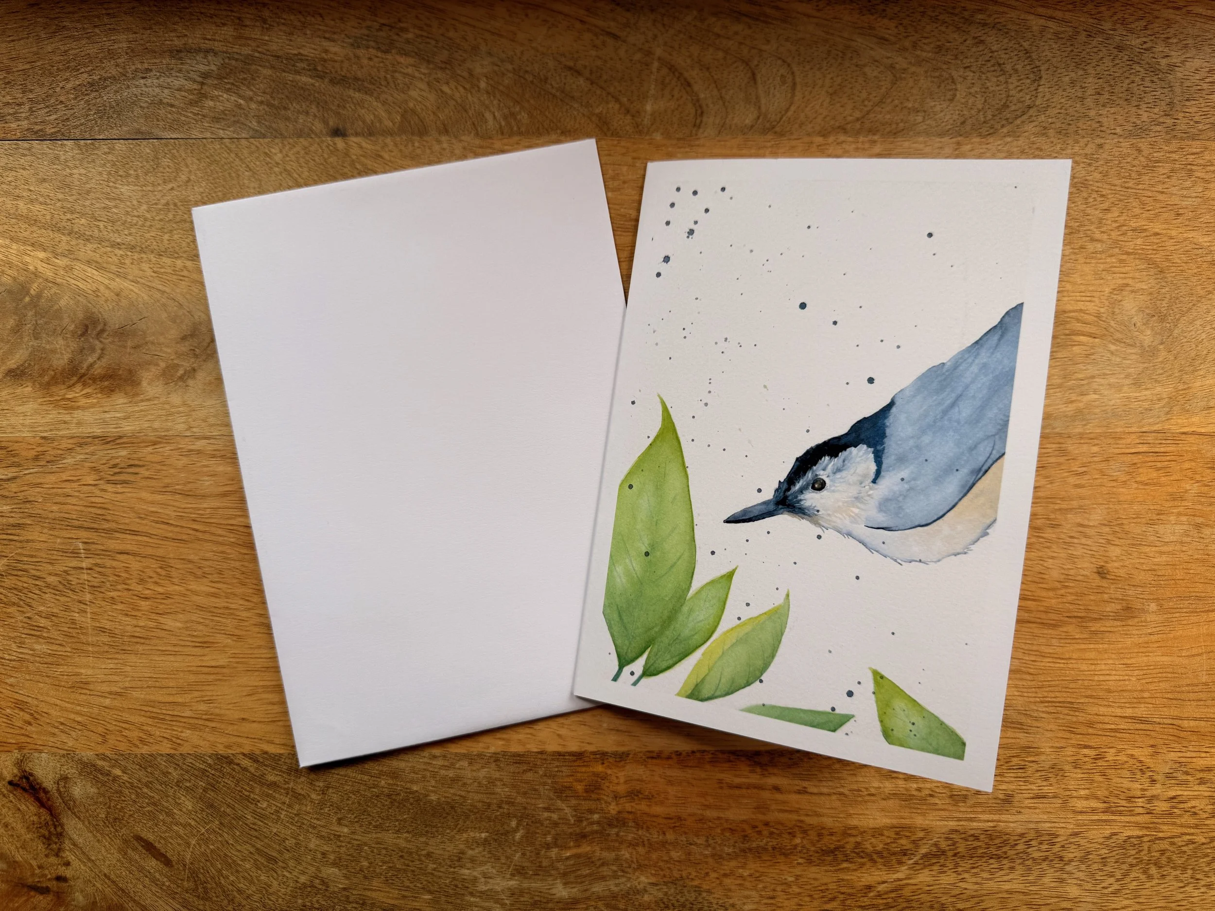 Studio-made greeting cards featuring reproductions of original watercolor artwork, displayed on a wooden tabletop in Monica Adams Art's studio shop.