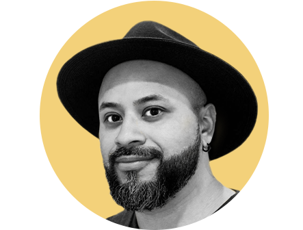 Black and white profile photo of latino man wearing a black fedora, and full grown beard.