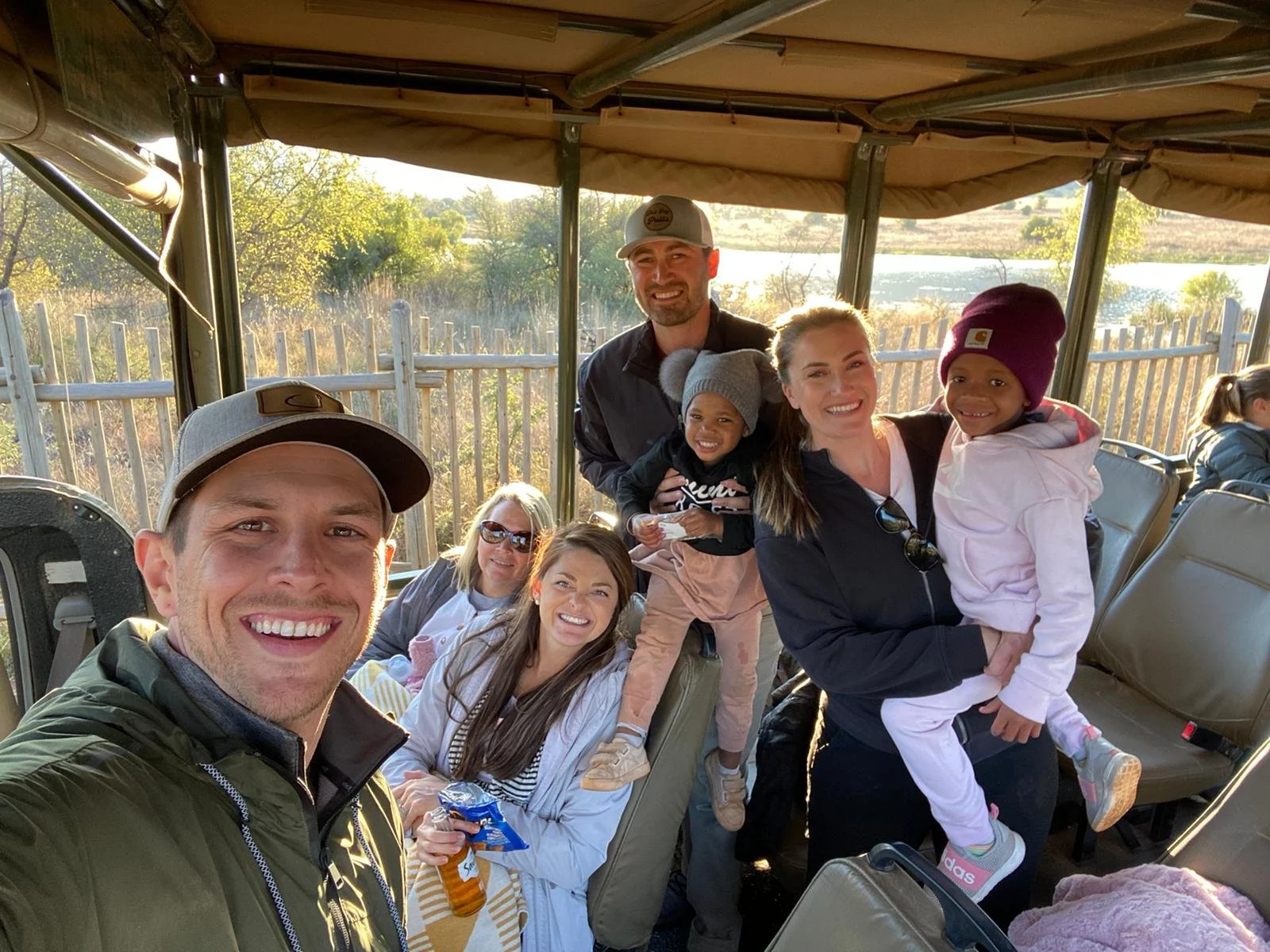 Just Another Wagner Adventure | Group of seven people, including children, posing for a selfie inside a safari vehicle with open sides. Pilanesberg National Park in South Africa.