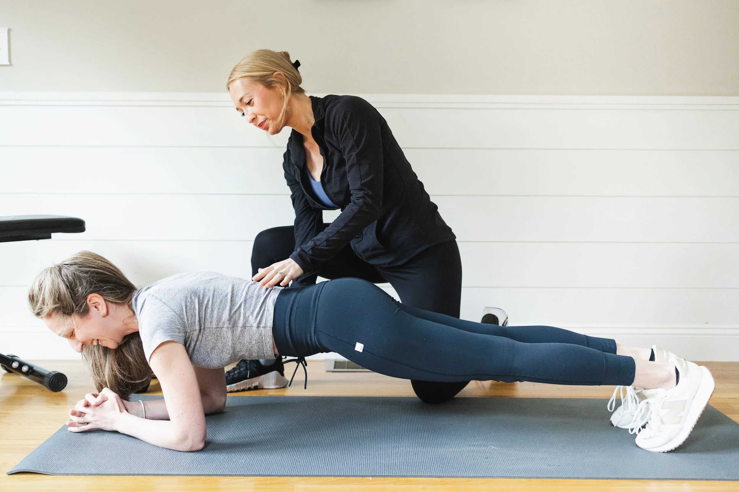 Diana Cross, certified personal trainer, coaches client on proper core engagement with plank form in south shore office.