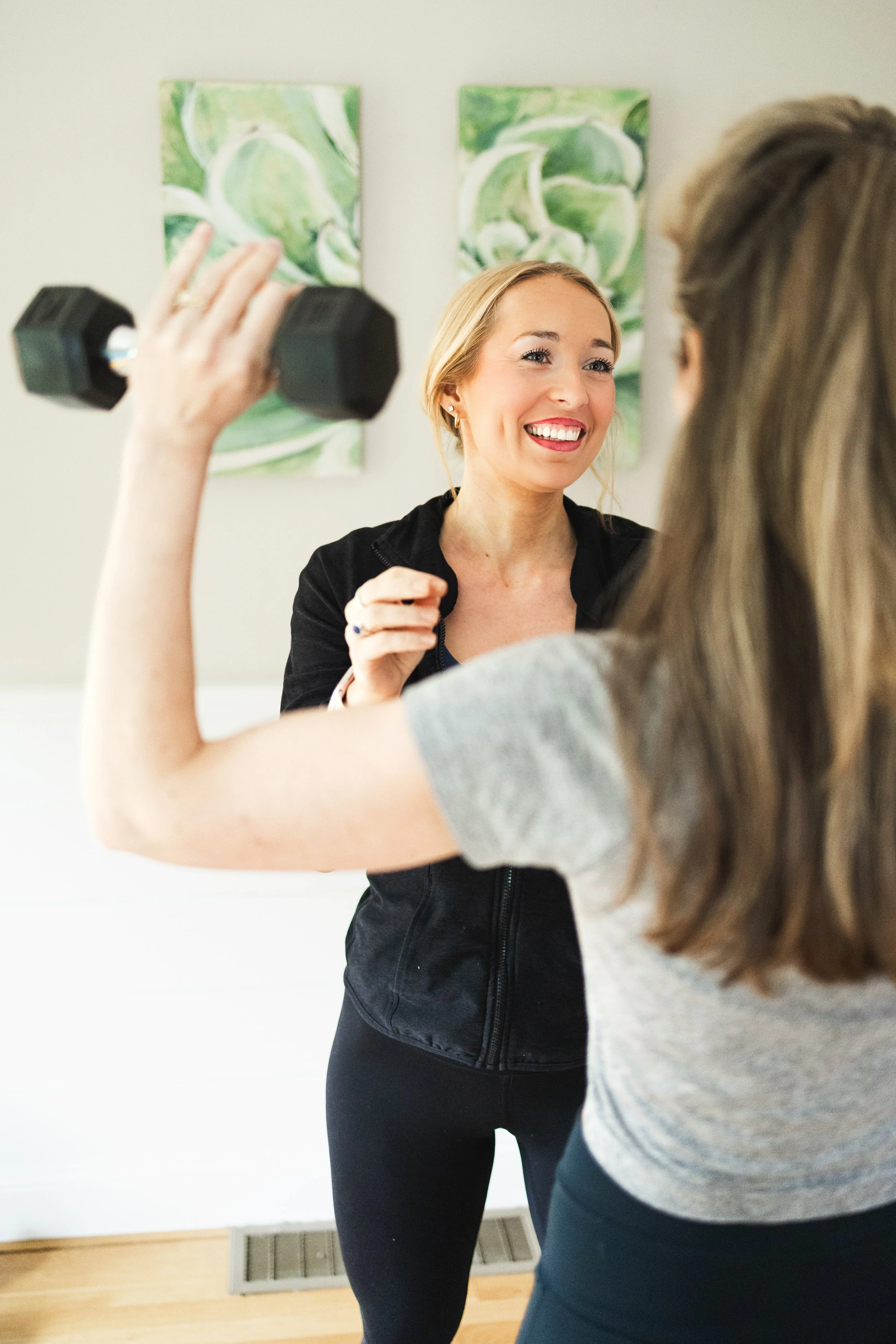 Diana Cross, Certified Personal Trainer, guides client on proper overhead press technique in south shore office.