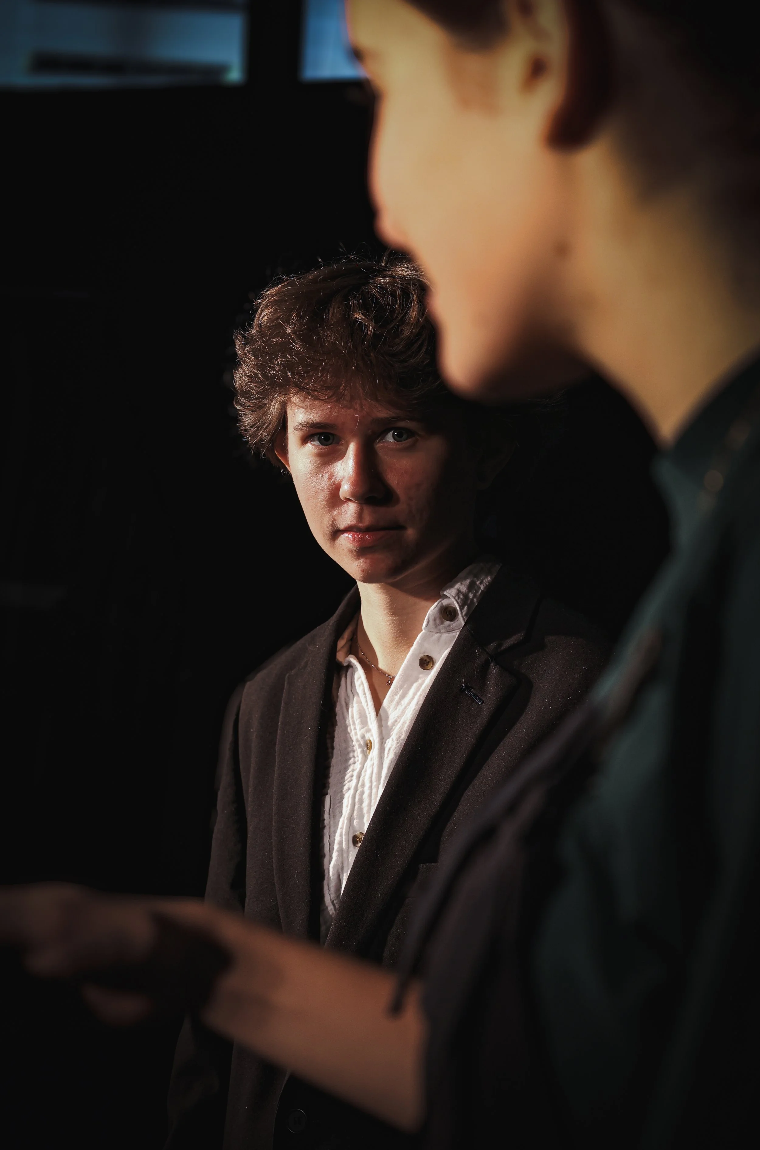 Zwei junge Männer im Gespräch, einer blickt direkt in die Kamera, der andere ist nur teilweise sichtbar.