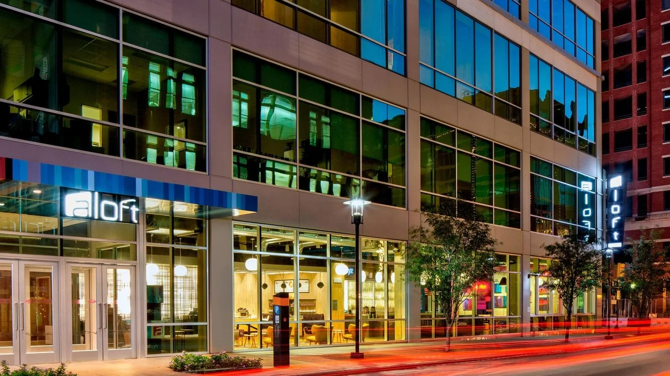 Nighttime city street view of a modern building with glass windows and illuminated
