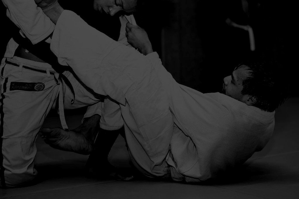 Two men practicing Brazilian Jiu-Jitsu, with one man on his back and the other man applying a submission hold.