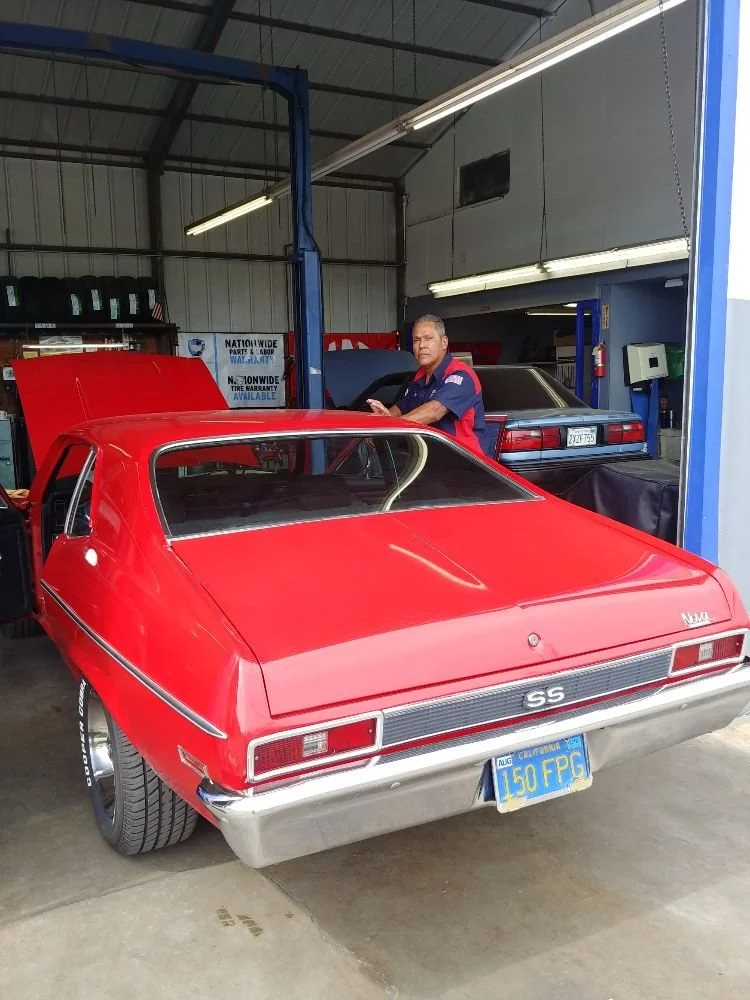 One of our mechanics standing next to a classic red car