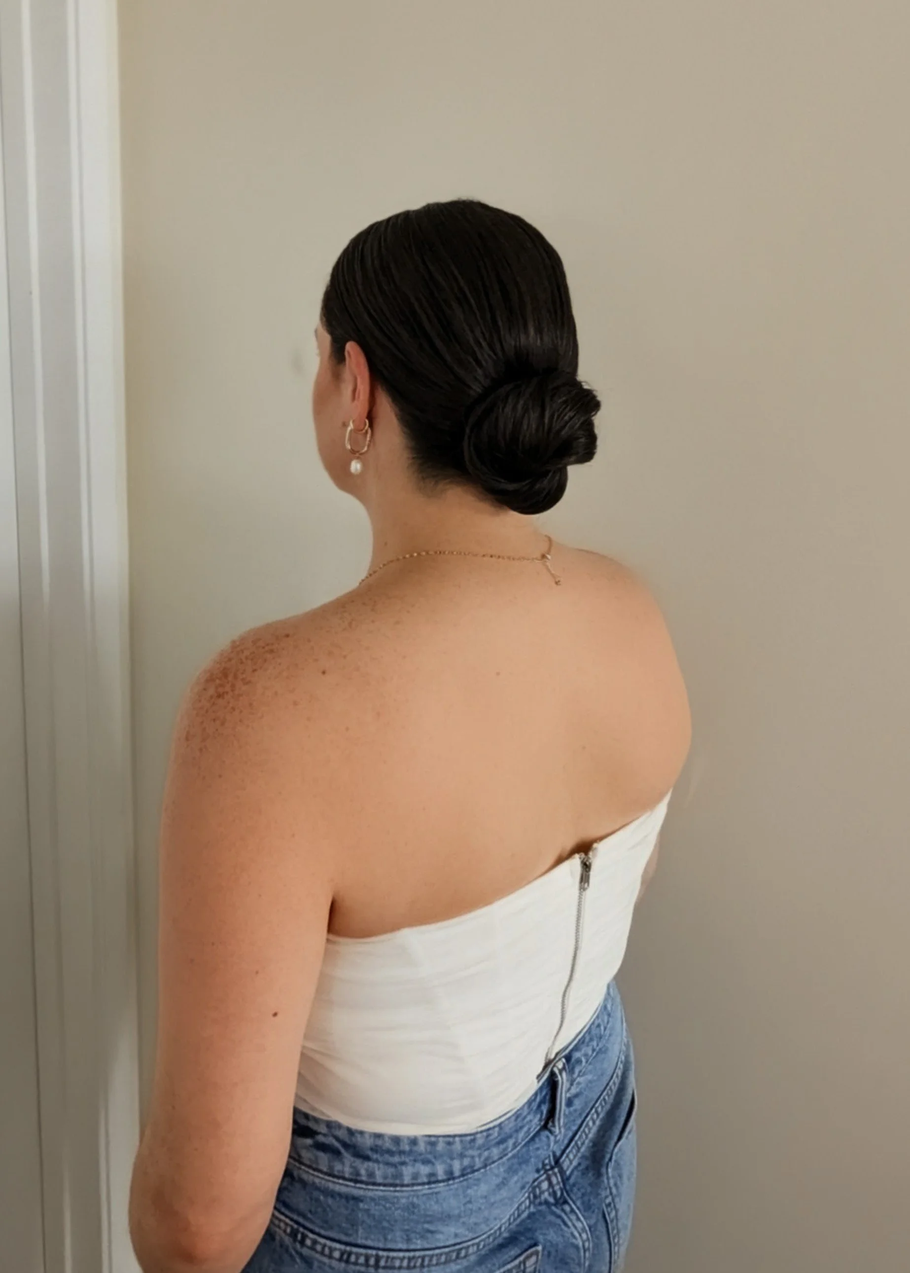 A woman with a clean low-bun had her hair styled by a bridal hairstylist in Vancouver, BC.