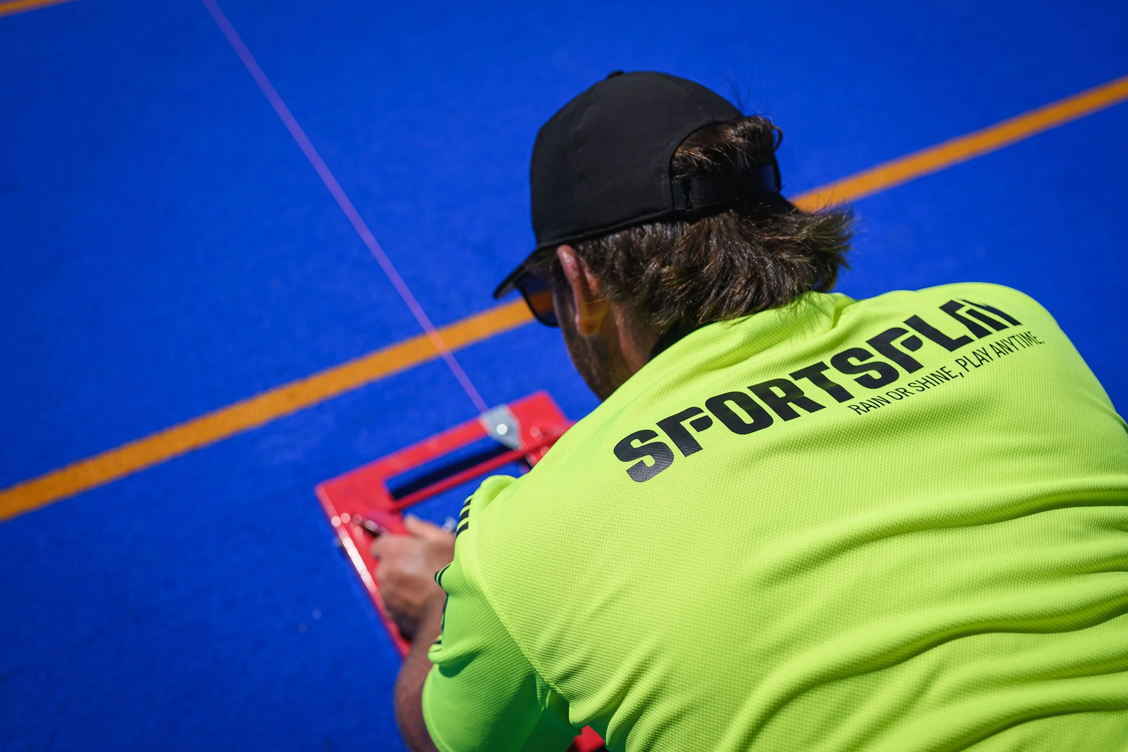Sportsplay employee, going through quality, safety, and compliance checklist on blue turf court.