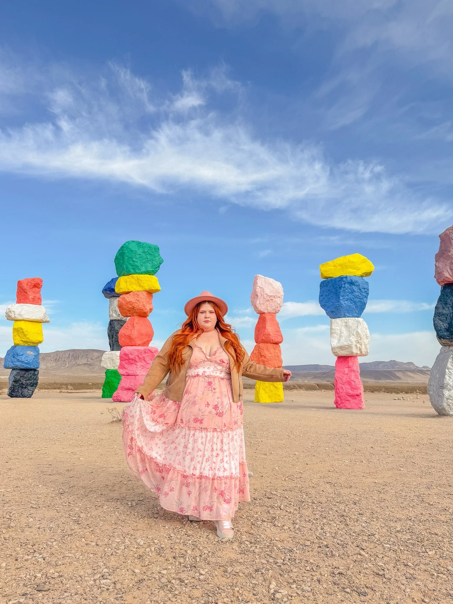 Plus size woman wearing a tiered maxi dress with a fedora and moto jacket in the desert