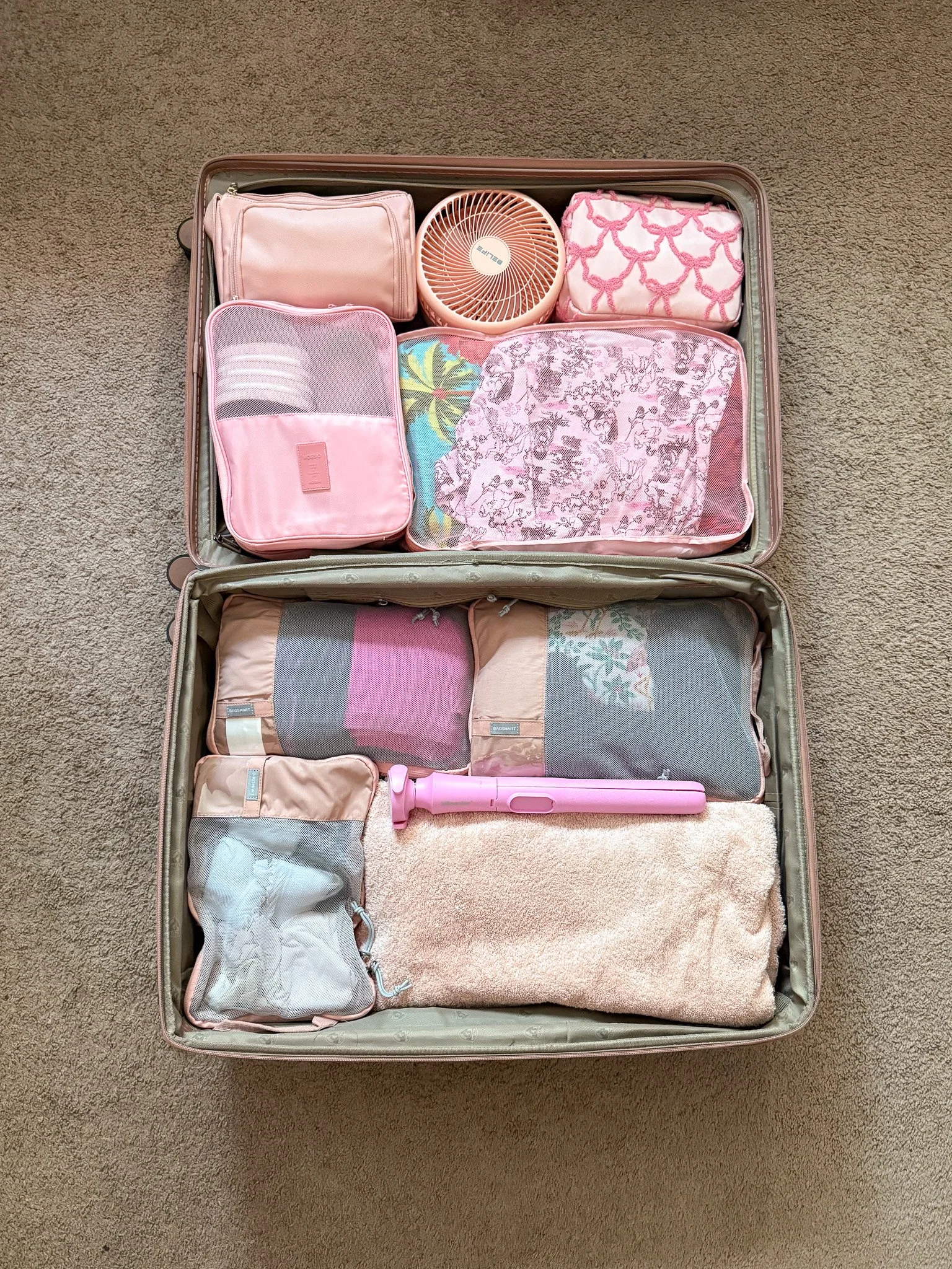 Open suitcase on the floor packed neatly with pink packing cubes.
