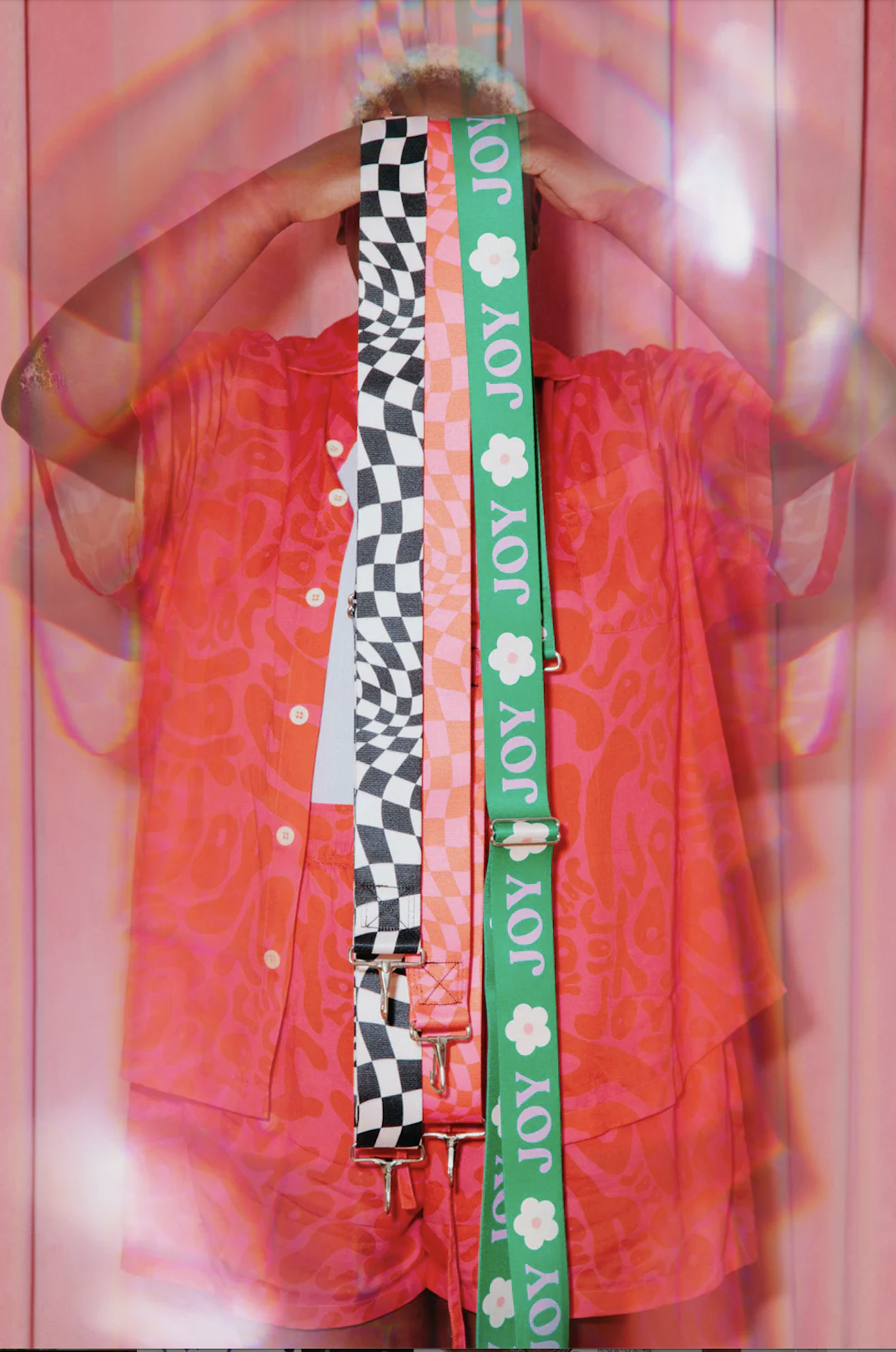 Woman holding up multiple plus size crossbody straps in fun, funky colors and patterns